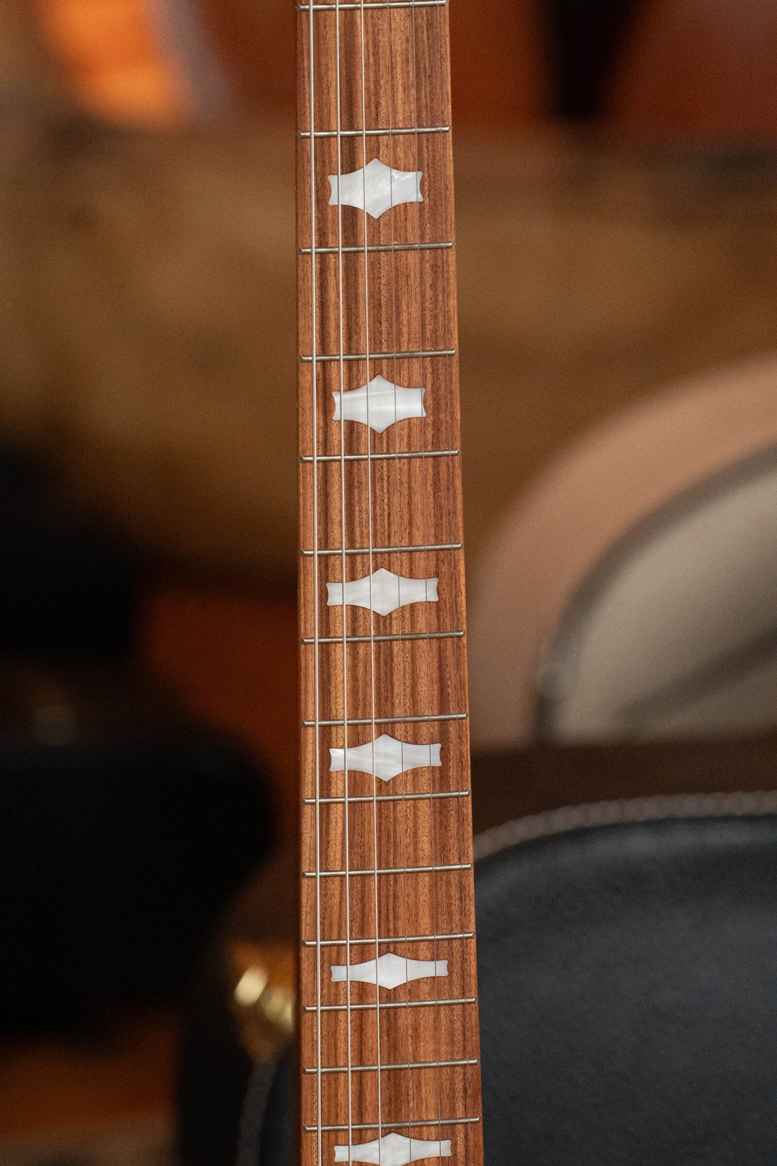 Close-up of a Deering Goodtime Six-R 6-String Resonator Banjo by Deering Banjos, showing its wooden neck with decorative white inlays, several frets, and part of the body; features Kavanjo Pickup #2520.