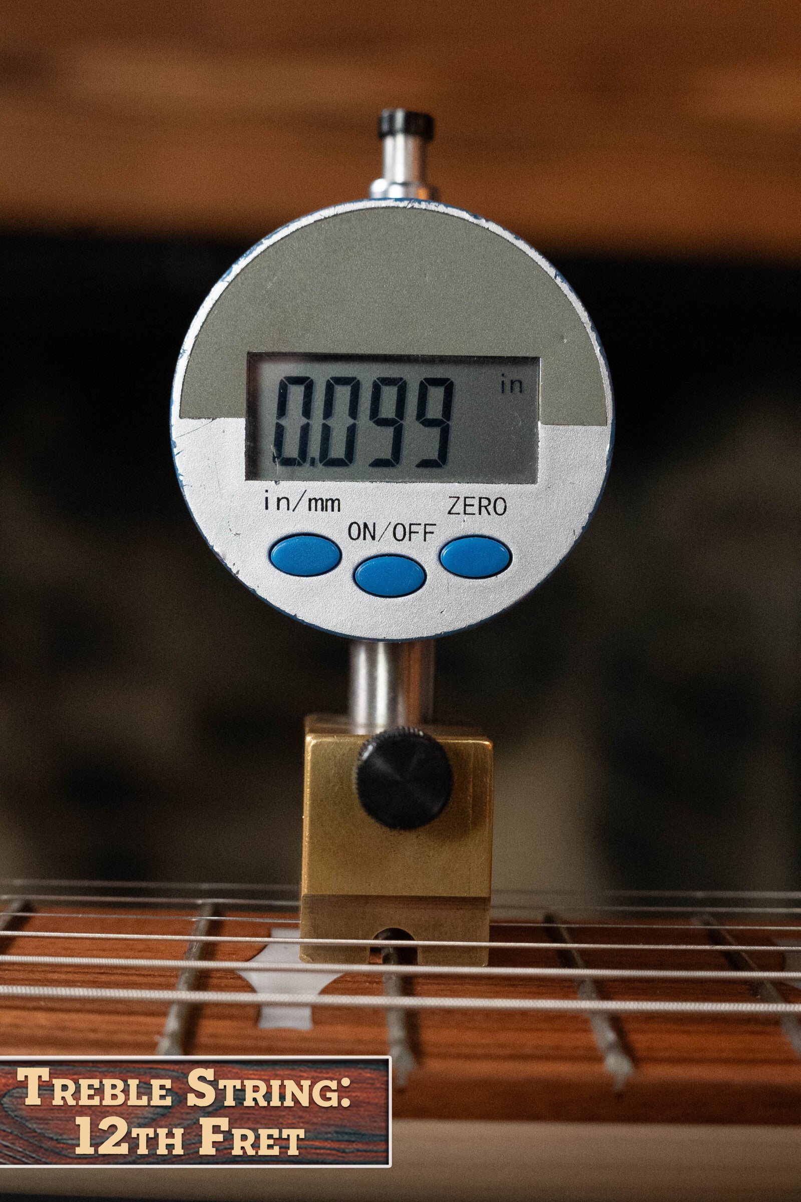 A digital gauge shows the treble string height at the 12th fret as 0.099 inches on a Deering Goodtime Six-R 6-String Resonator Banjo w/Kavanjo Pickup (#2520) by Deering Banjos. Label: Treble String: 12th Fret.