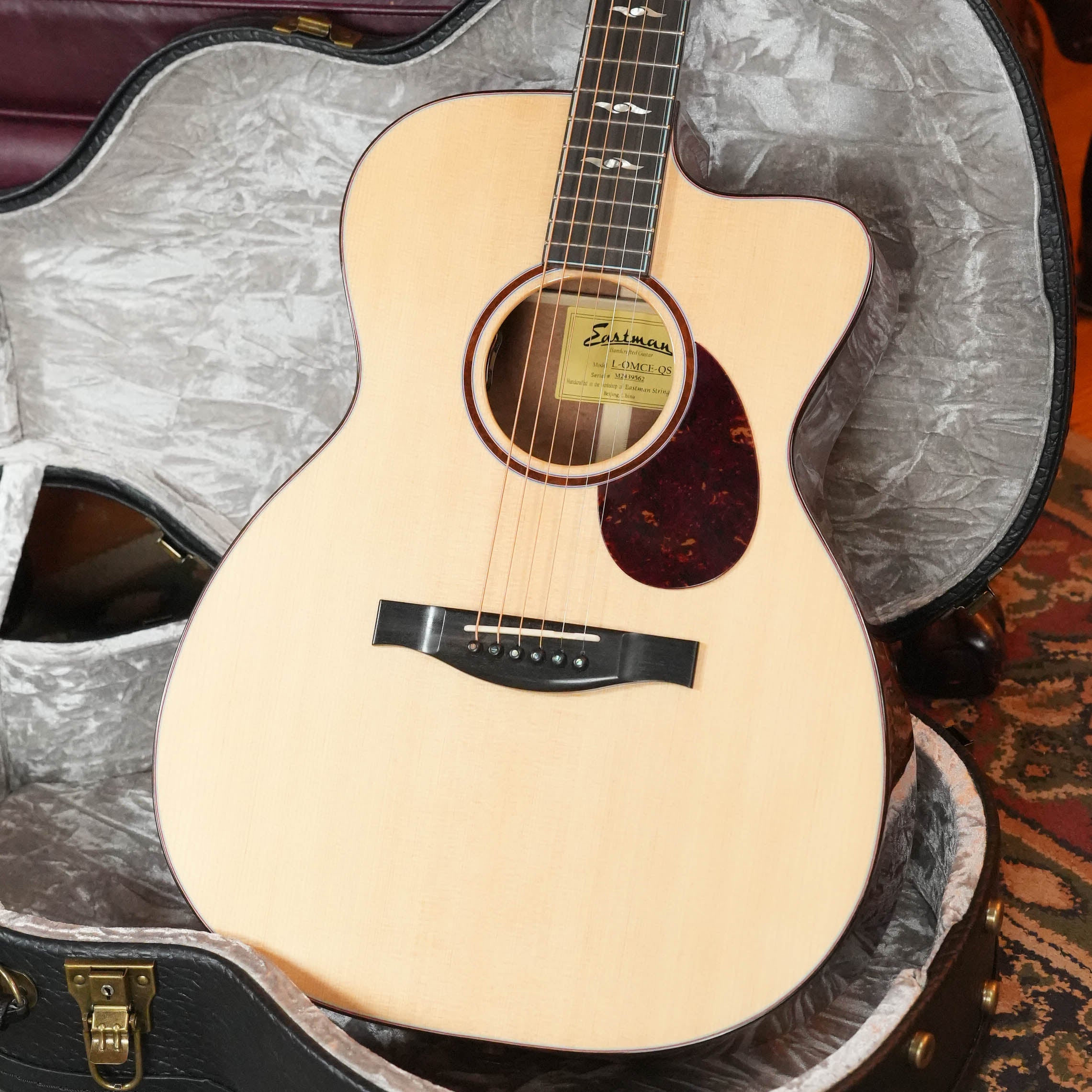 A *Dread-Not Certified Used* 2024 Eastman Guitars L-OMCE-QS Orchestra Model Acoustic-Electric Guitar with solid Engelmann spruce top, solid quilted sapele back and sides, LR Baggs VTC, rests in a gray-lined padded hard case.