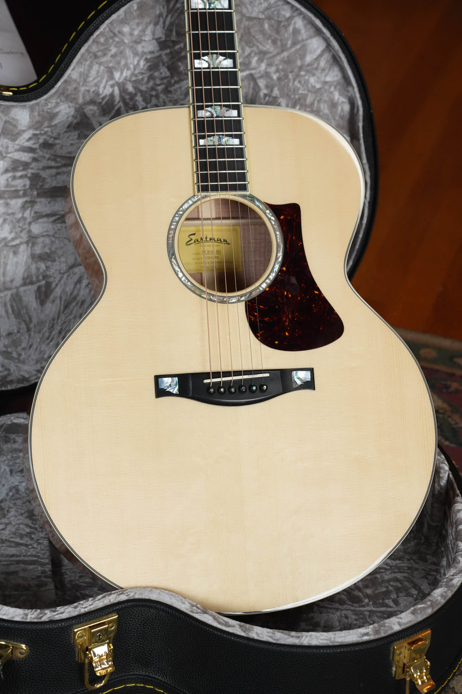 The (Used) Eastman AC630-BD Engelmann Spruce/Flamed Maple Blonde Jumbo Acoustic Guitar #7984 by Eastman Guitars features decorative fretboard inlays, a tortoiseshell pickguard, and comes in a padded gray case with a glossy light finish.