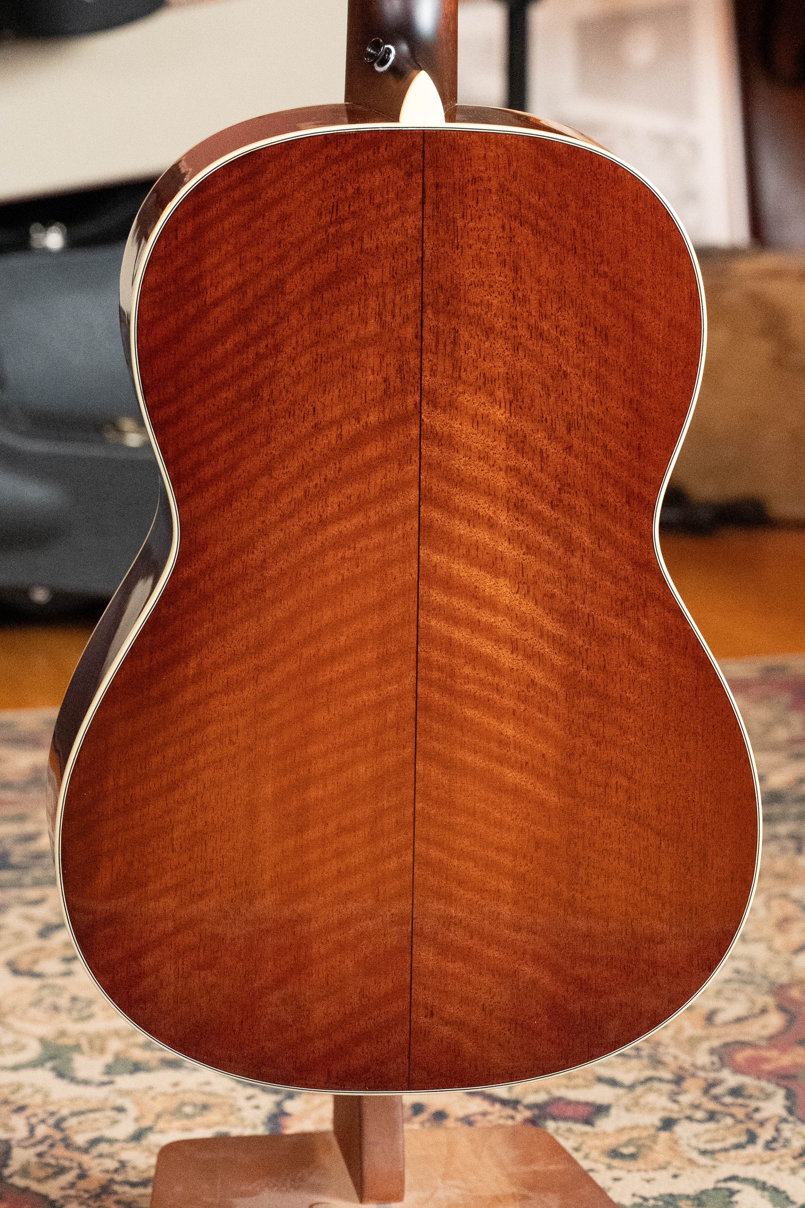 A close-up of the *Dread-Not Certified Used* Eastman E6-LGSS-TC-SB Thermo-Cured Sitka/Mahogany Slope Shoulder Sunburst Acoustic Guitar (#9323) by Eastman Guitars, upright on a wooden stand atop a patterned rug.