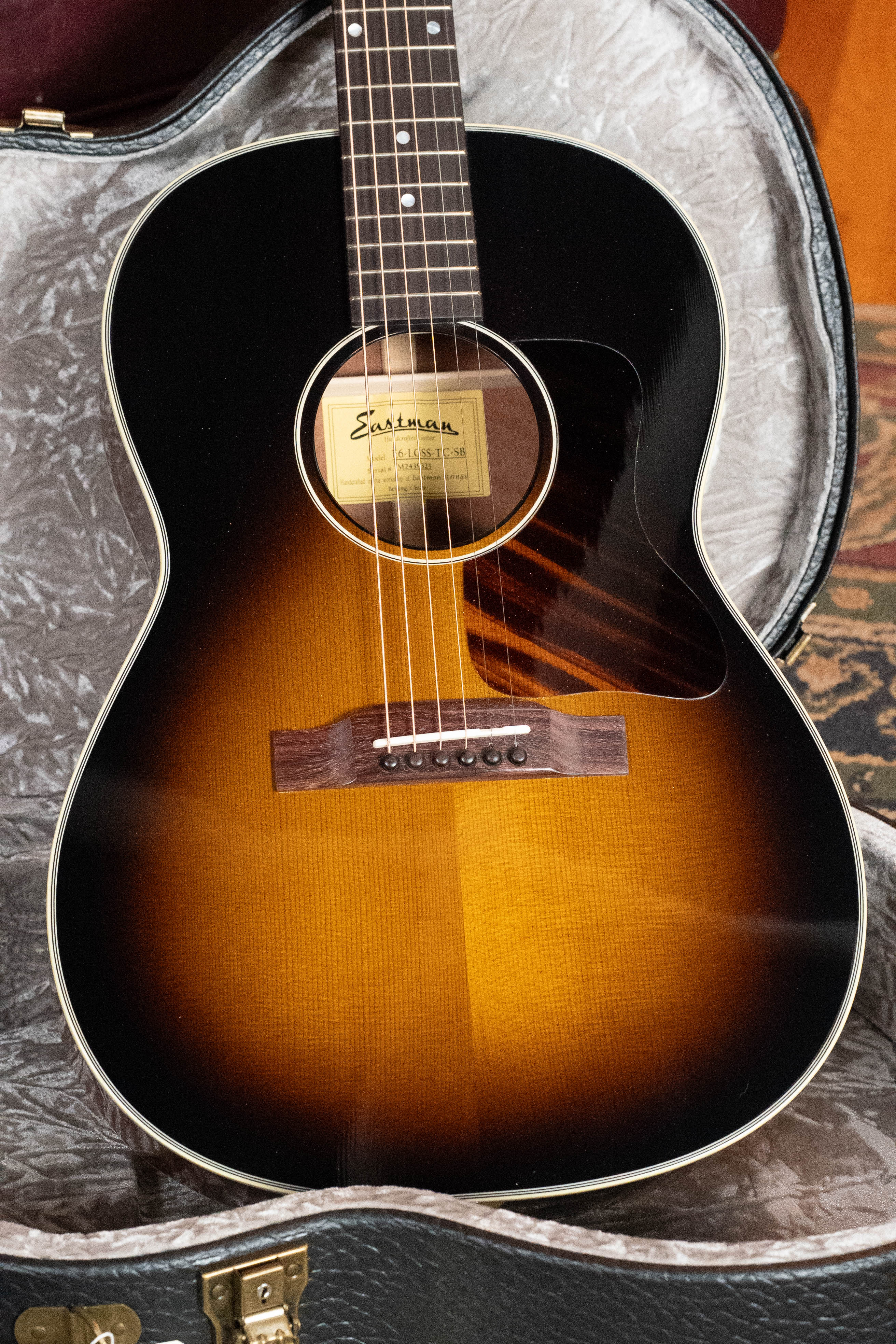 An Eastman Guitars *Dread-Not Certified Used* E6-LGSS-TC-SB Slope Shoulder Sunburst Acoustic Guitar #9323 with a glossy finish, thermo-cured Sitka spruce top, tortoiseshell pickguard, and visible sound hole label rests in an open hardshell case.