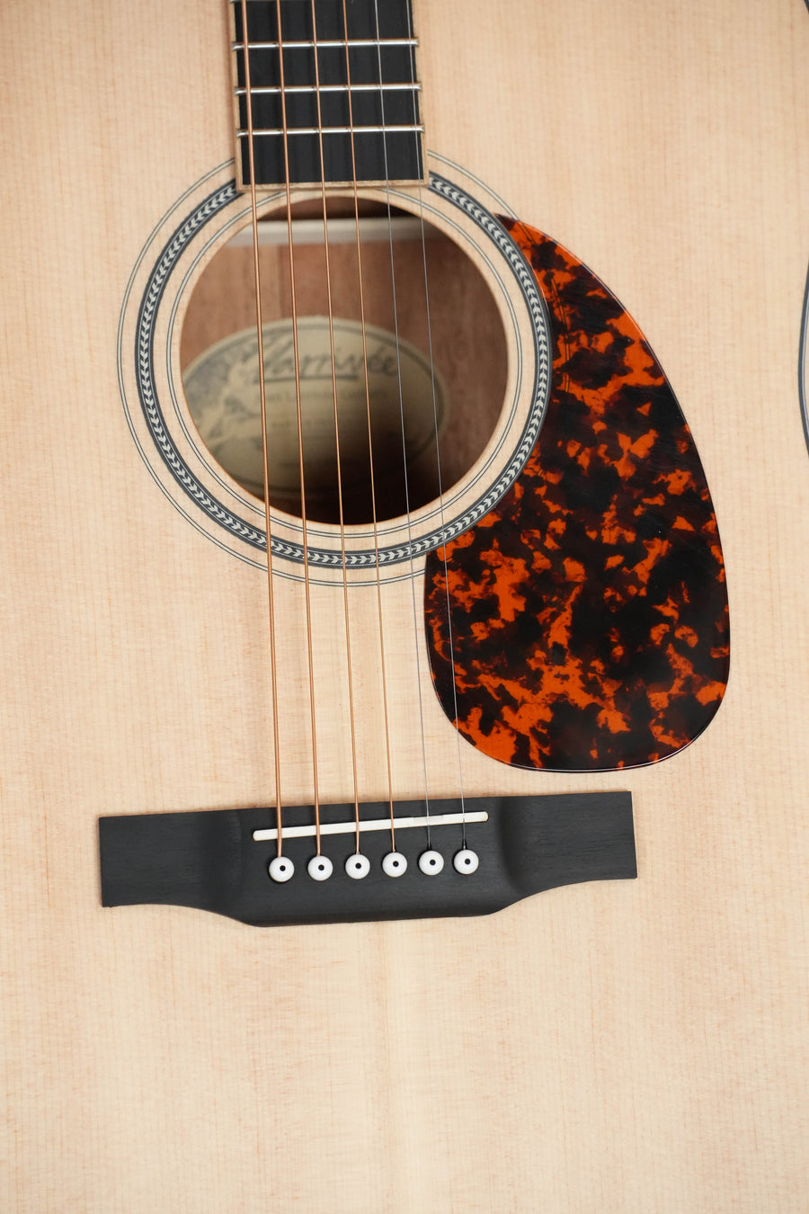 Close-up of a *Dread-Not Certified Used* Larrivée D-03 Sitka/Mahogany Dreadnought Acoustic Guitar #3382, showing part of the sound hole, rosette, tortoiseshell pickguard, strings, and bridge on a solid Sitka spruce top.