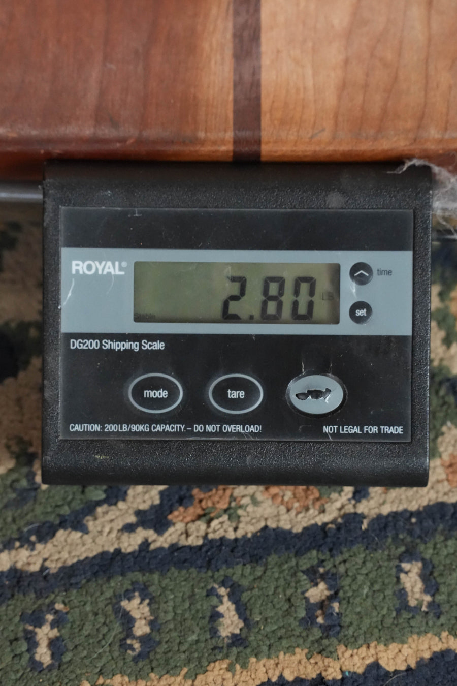 A digital shipping scale displays 2.80 pounds. Resting partly on the scale and patterned carpet is a Bourgeois *Dread-Not Certified* M5-O-BT Aged Tone Adirondack/European Curly Maple Black Octave Mandolin #2108.