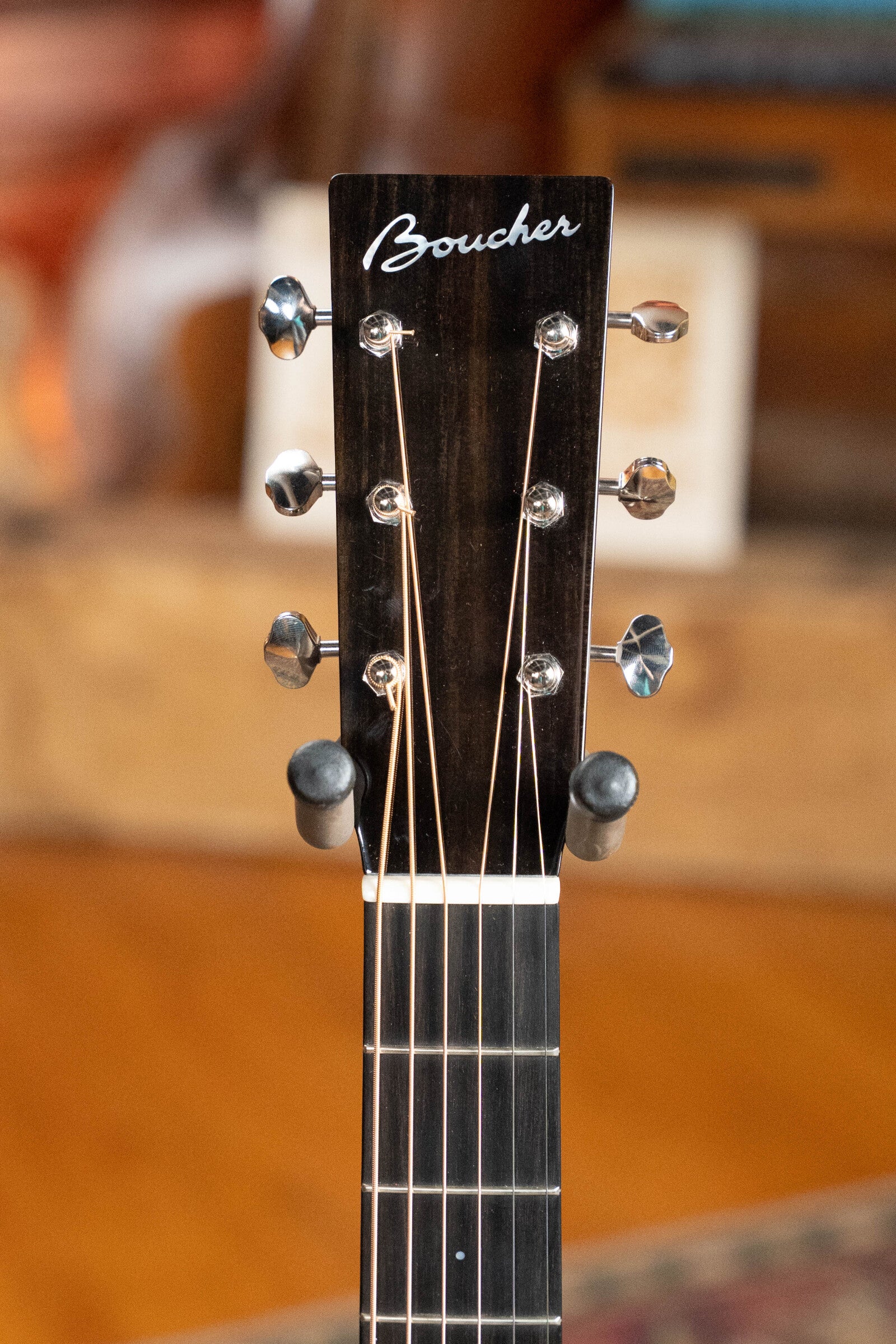 Close-up of the headstock of a Boucher Guitars Dread-Not Certified Used BG-52-GM Bluegrass Goose Series Dreadnought (#1339), crafted with torrefied master grade Adirondack Red Spruce, showing tuning pegs and strings against a blurred background.