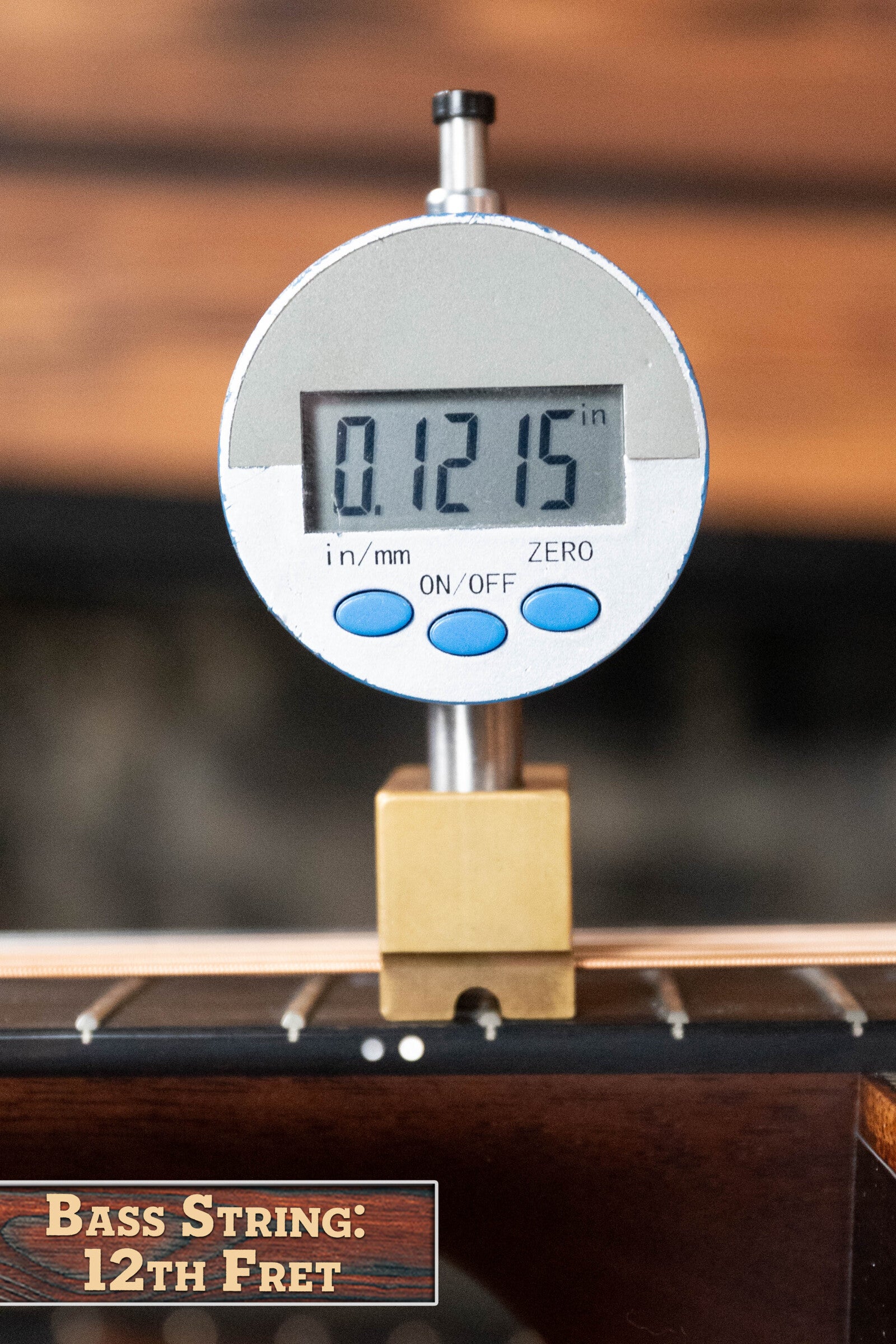 A digital gauge reads 0.1215 inches, showing the bass string height at the 12th fret of a *Dread-Not Certified Used* Boucher BG-52-GM Bluegrass Goose Series dreadnought from Boucher Guitars—perfect for precise setups. Label: Bass String: 12th Fret.