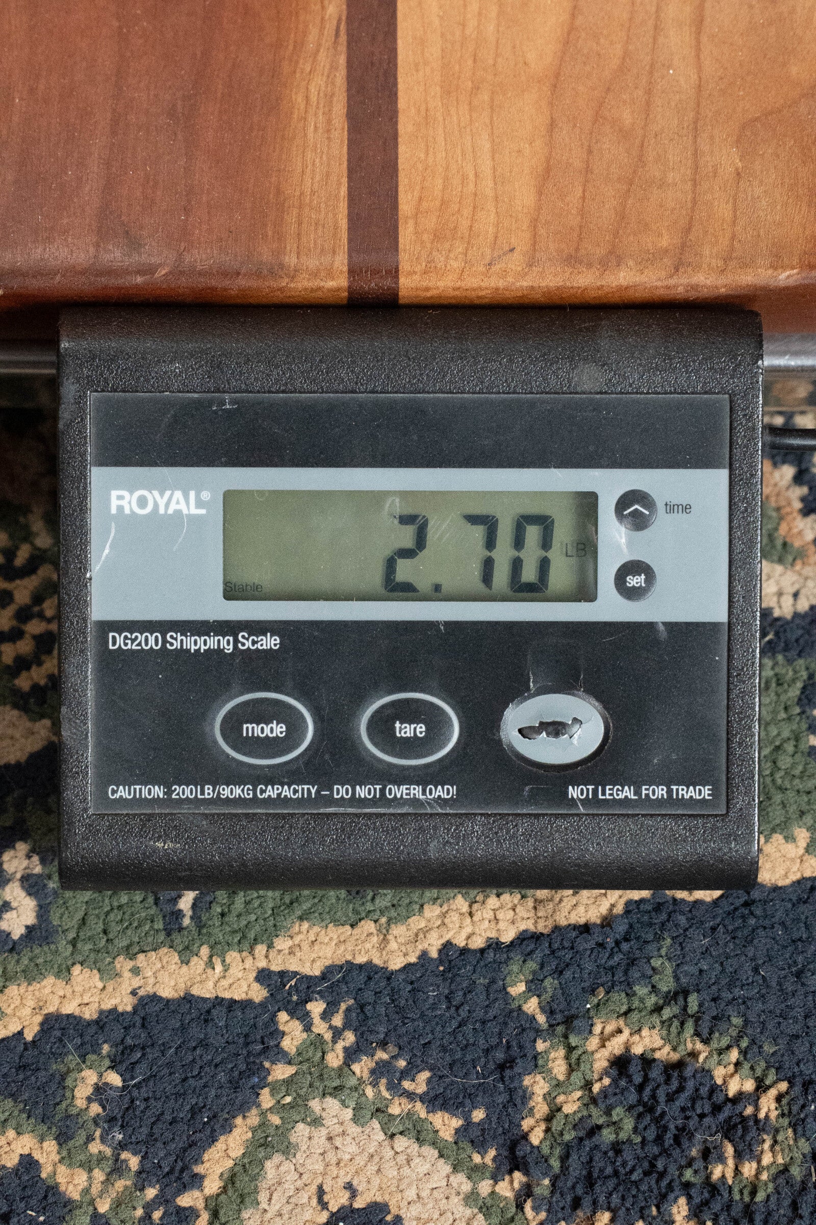 A black digital shipping scale shows 2.70 lbs on a patterned carpet, with mode, tare, and set buttons. Above it, part of an Eastman Guitars *Dread-Not Certified Used* MDA815 F-Style Mandola Classic Finish #4978 is visible.