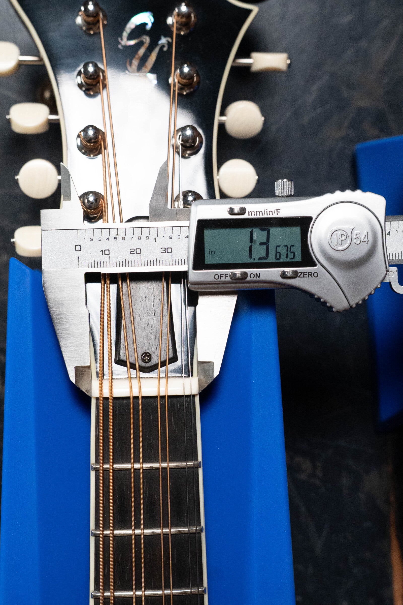 A digital caliper measures the nut width of a *Dread-Not Certified Used* Eastman Guitars MDA815 F-Style Mandola Classic Finish #4978 at 1.3675 inches, with its headstock and strings resting on a blue support.
