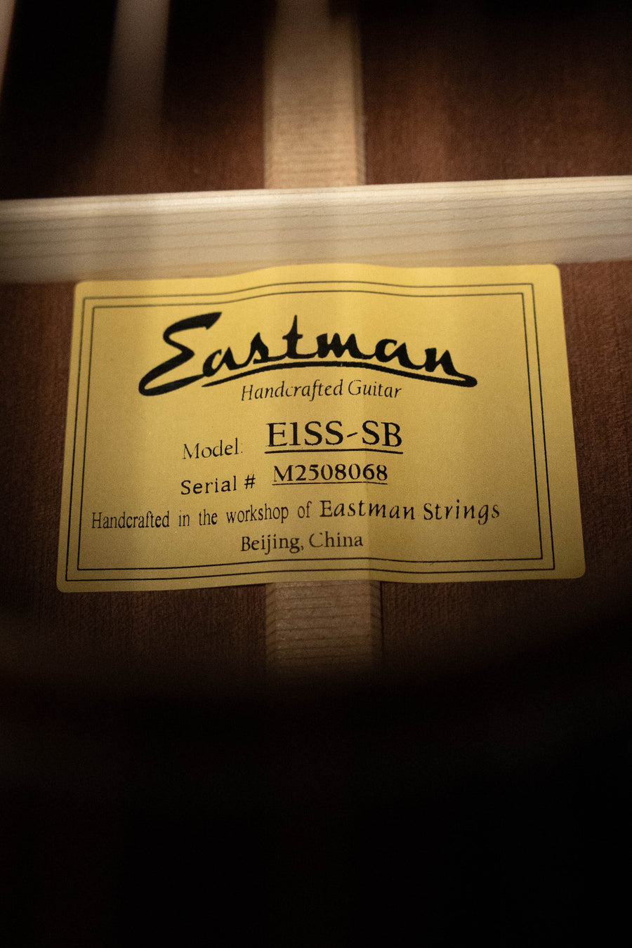 Close-up of a yellow label inside an Eastman Guitars E1SS-SB Sitka/Sapele Sunburst Slope Shoulder Dreadnought Acoustic Guitar #8068, handcrafted in Beijing, China.