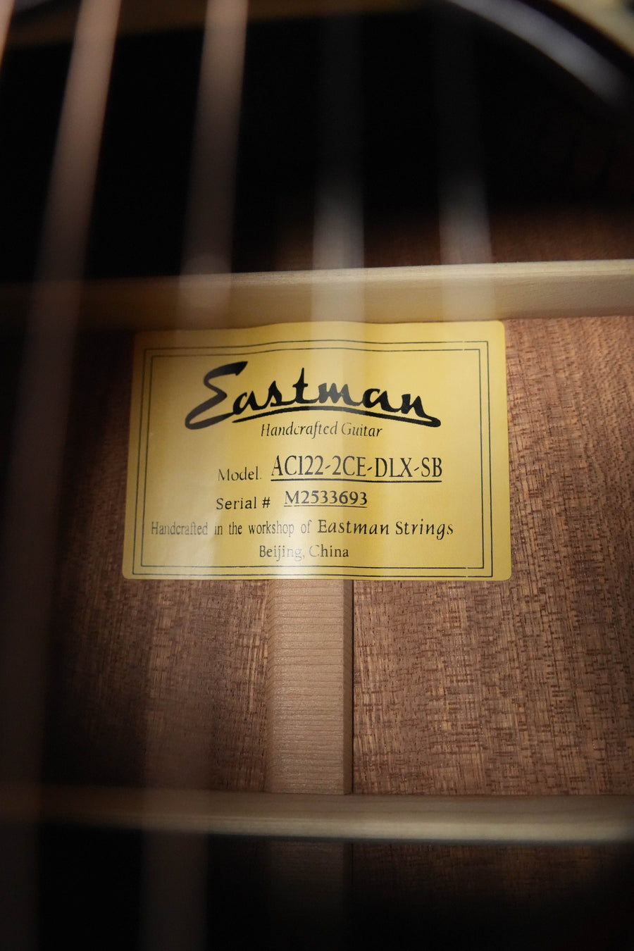 Close-up of a label inside the soundhole showing Eastman Guitars AC122-2CE-DLX-SB Cedar/Sapele Sunburst Cutaway Grand Auditorium Guitar w/Fishman Pickup, serial #3693, handcrafted in Beijing, China.