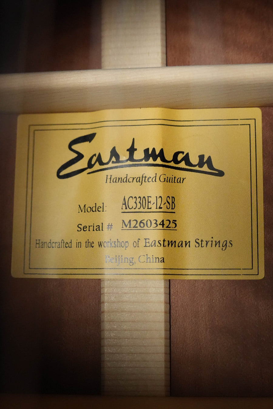 A close-up label inside an Eastman Guitars AC330E-12-SB Sitka/Mahogany Jumbo 12-String Sunburst w/LR Baggs Pickup #3425 reads: Handcrafted in the workshop of Eastman Strings, Beijing, China.