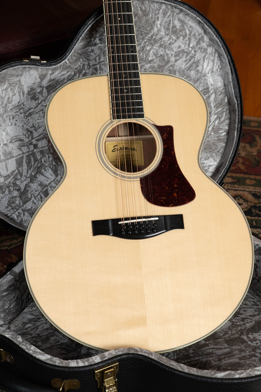 An Eastman Guitars AC330E-12 Sitka/Mahogany Jumbo 12-String Guitar w/LR Baggs Pickup (#7301) with a dark pickguard sits in an open hard case lined with soft gray fabric.