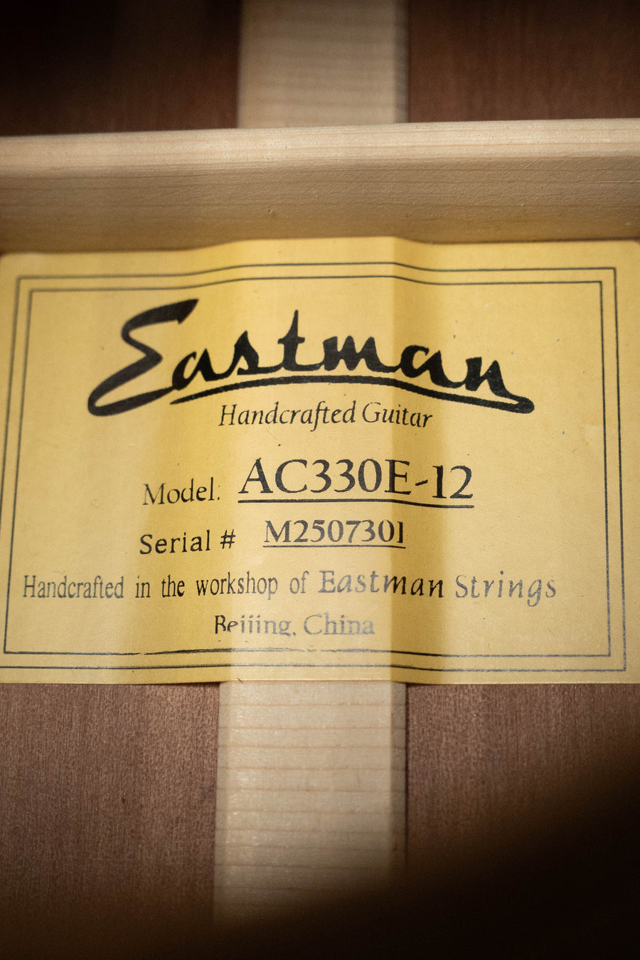 Yellow label inside this jumbo guitar reads: Eastman Guitars AC330E-12 Sitka/Mahogany 12-String w/LR Baggs Pickup, Serial #7301, handcrafted in Beijing, China.