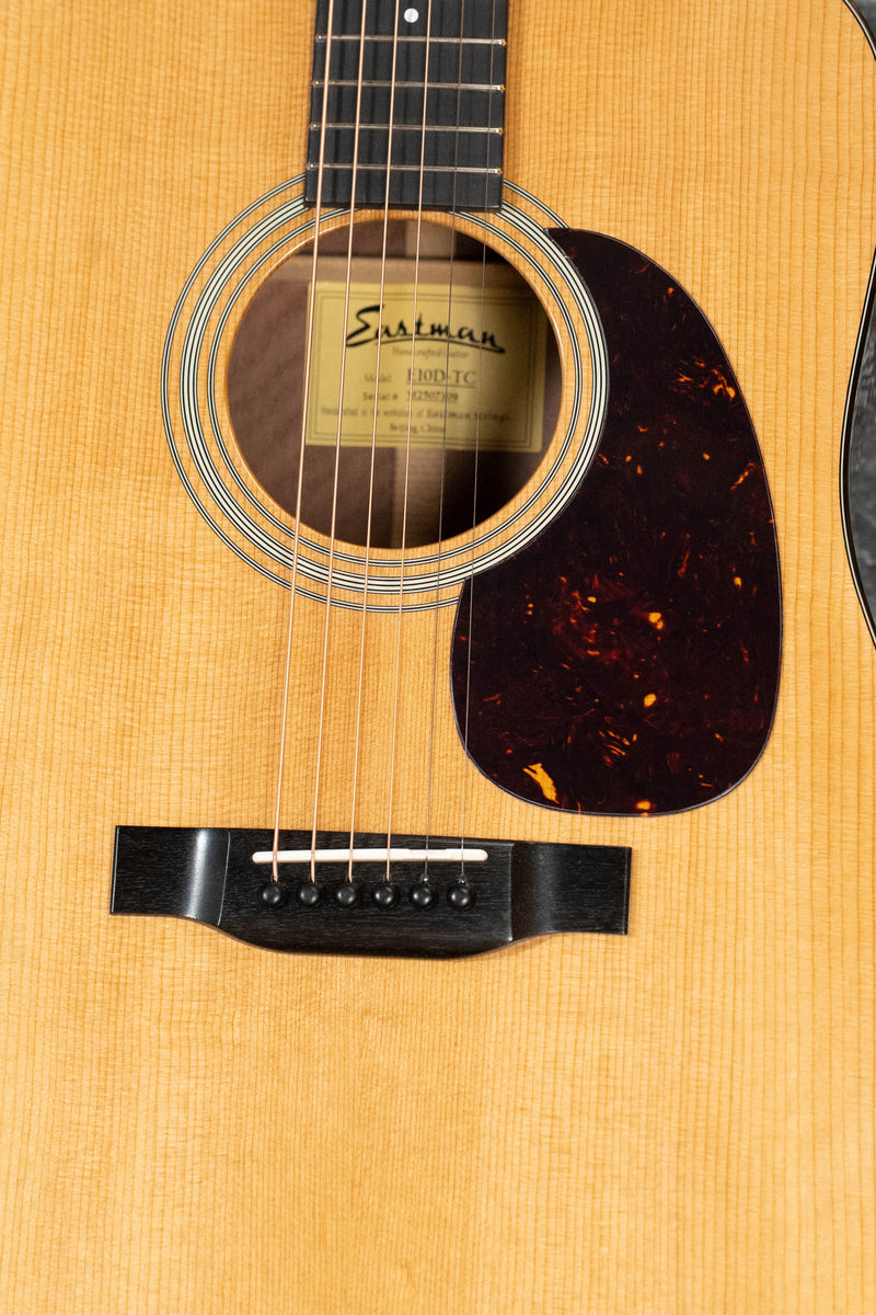 Close-up of the Eastman Guitars E10D-TC Thermo-Cured Adirondack/Mahogany Dreadnought Acoustic Guitar #7309, showing its light wood body, dark pickguard, visible strings, and label inside the sound hole for a vintage-inspired look.