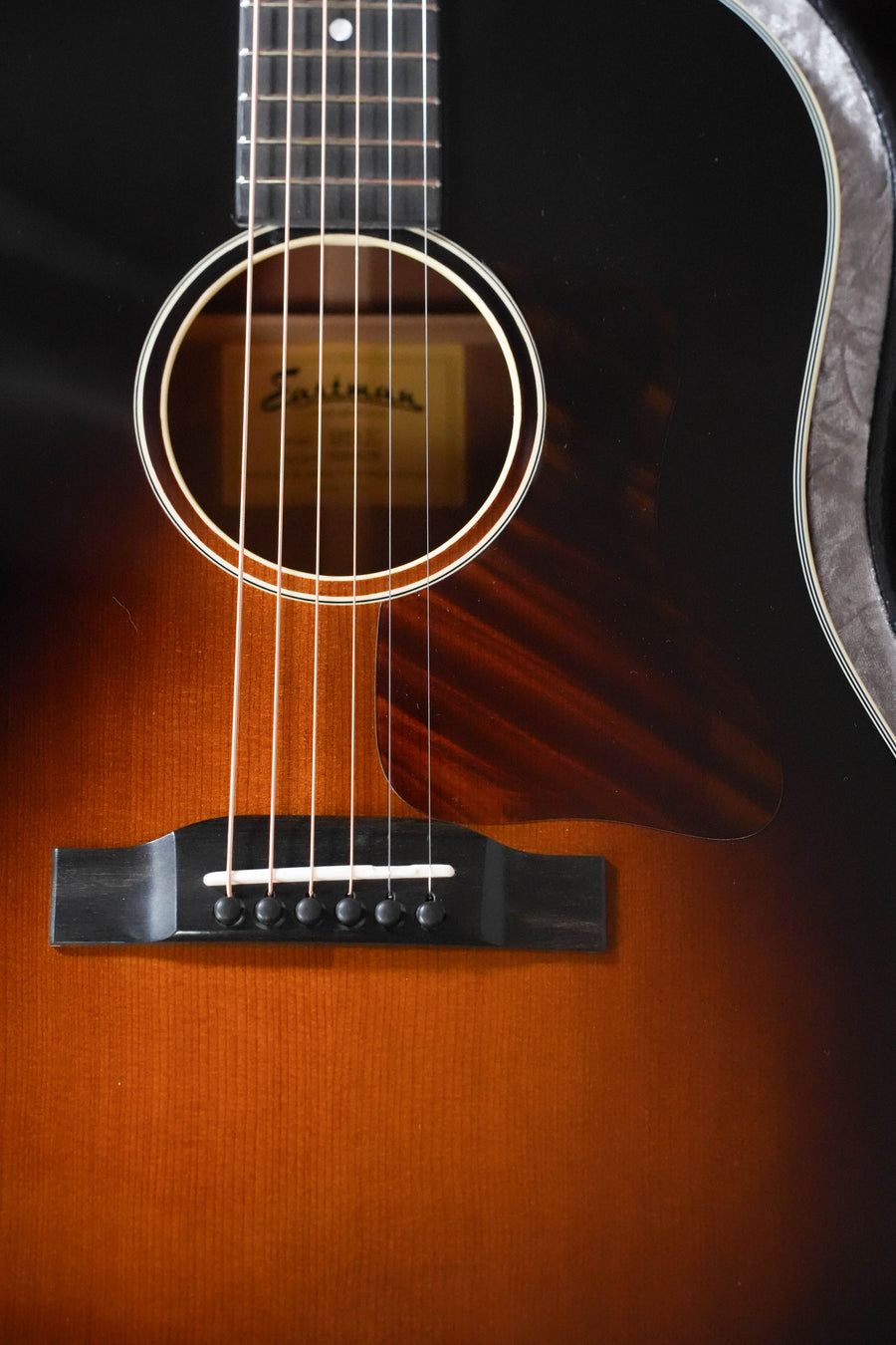 Close-up of the Eastman Guitars E10SS-TC Thermo-Cured Adirondack/Mahogany Sunburst Slope Shoulder Dreadnought Acoustic Guitar #0378, showcasing its strings, soundhole, and part of its glossy sunburst finish.
