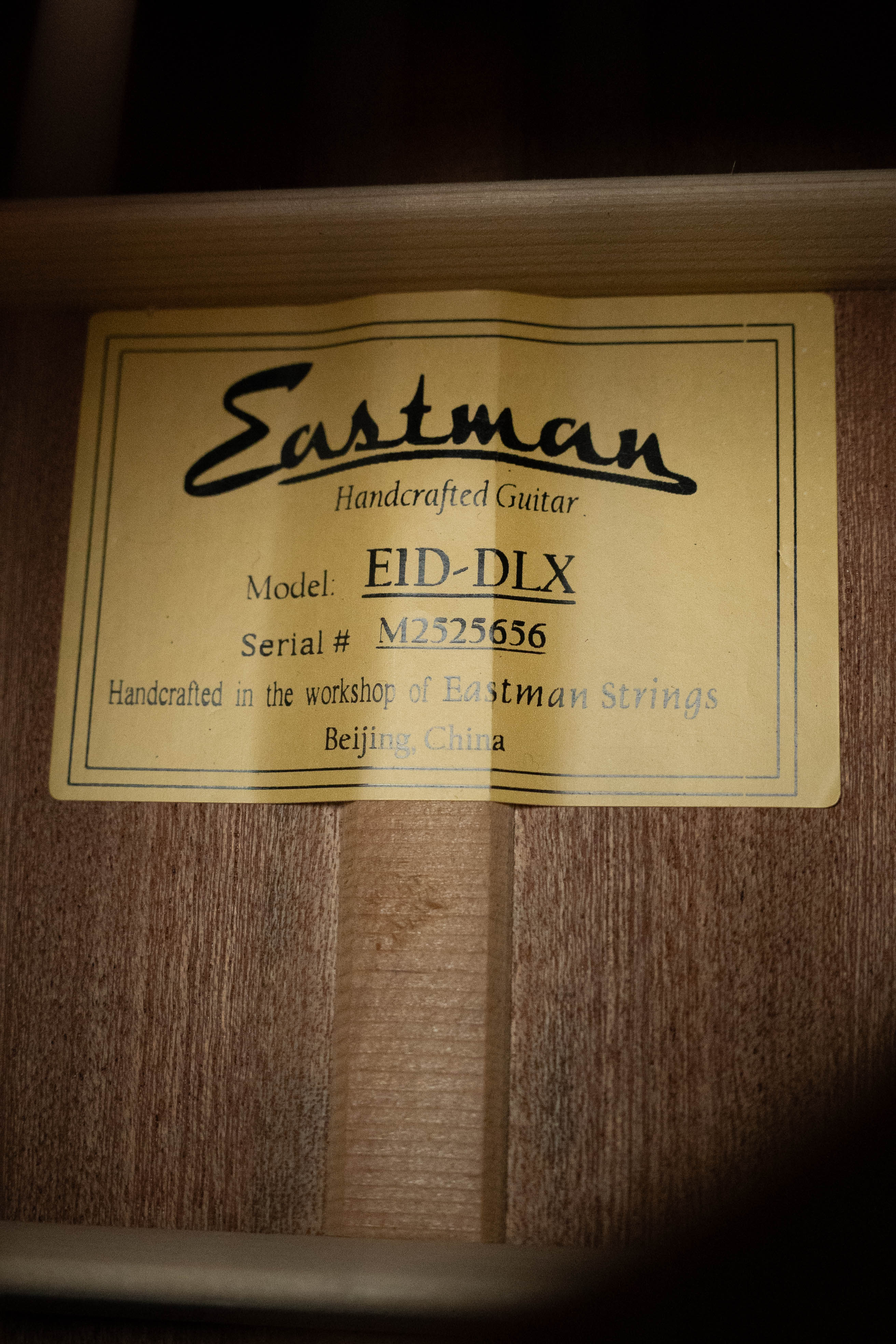A yellow label inside the Eastman E1D-DLX Sitka/Sapele Dreadnought Guitar w/Fishman Pickup #5656 reads: “Eastman Guitars, Model: E1D-DLX, Serial #: 5656, Handcrafted in the workshop of Eastman Strings, Beijing, China.”.