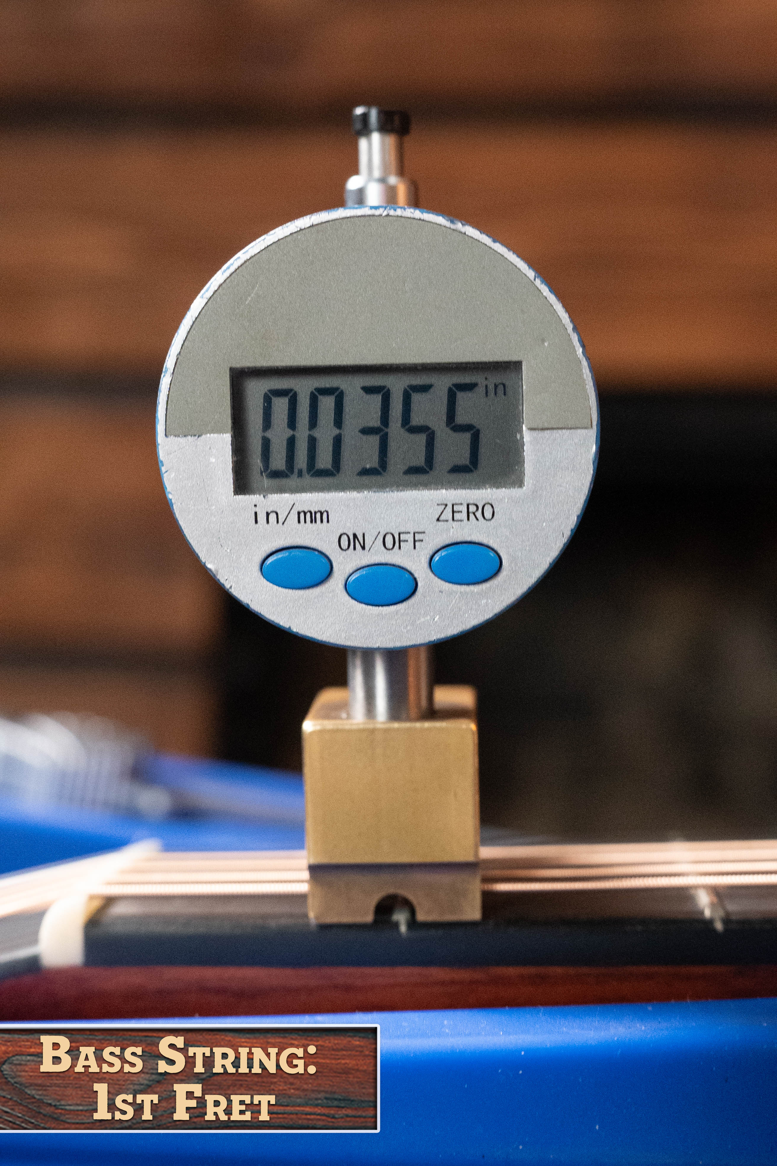A digital caliper reads 0.0355 inches as it measures the bass string height at the 1st fret of an Eastman E1D-DLX Sitka/Sapele Dreadnought Guitar w/Fishman Pickup #5656 by Eastman Guitars.
