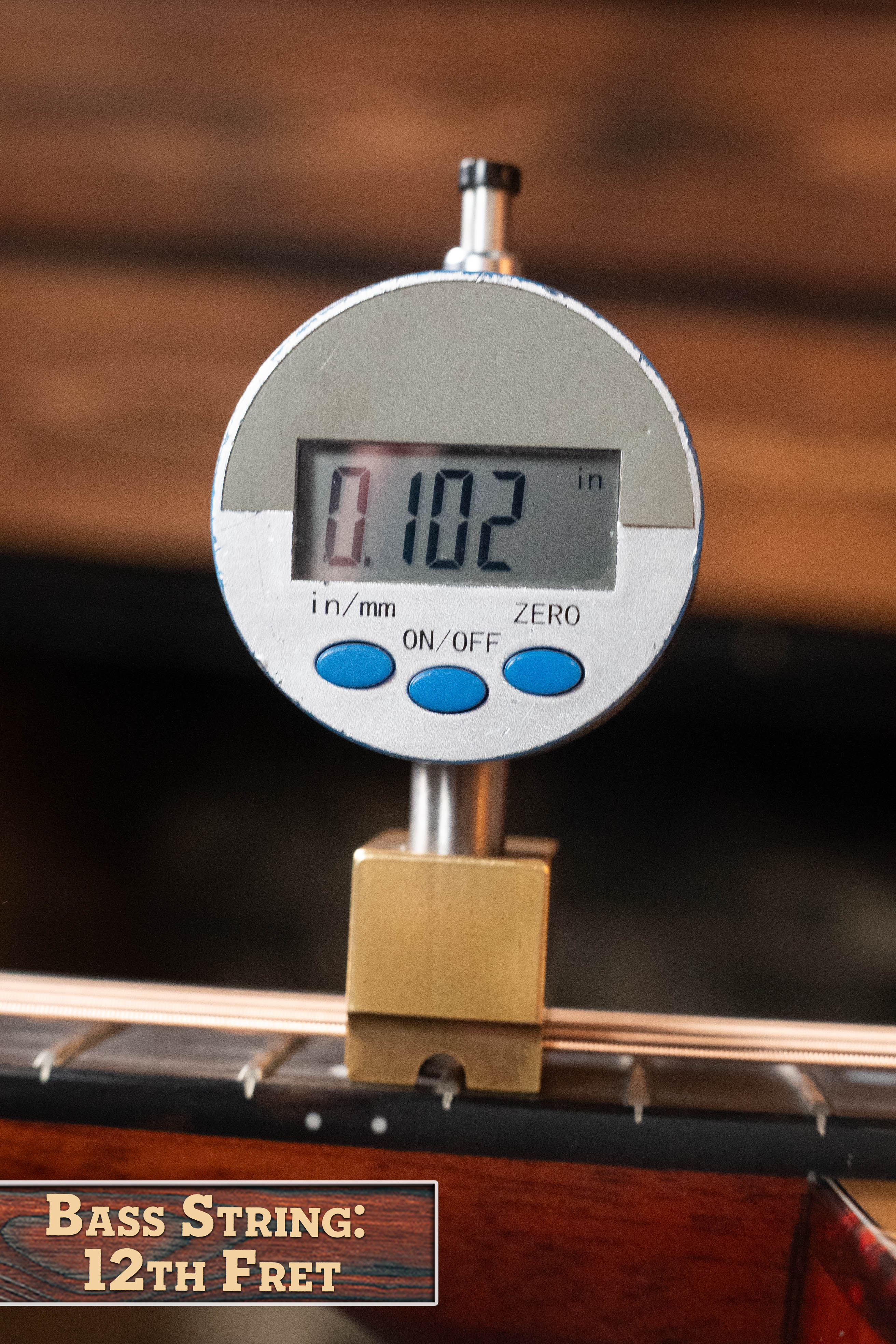 A digital gauge reads 0.102 inches while checking bass string height at the 12th fret—ideal for players adjusting action on their Eastman Guitars E1D-DLX Sitka/Sapele Dreadnought w/Fishman Pickup #5656. Label: Bass String: 12th Fret.