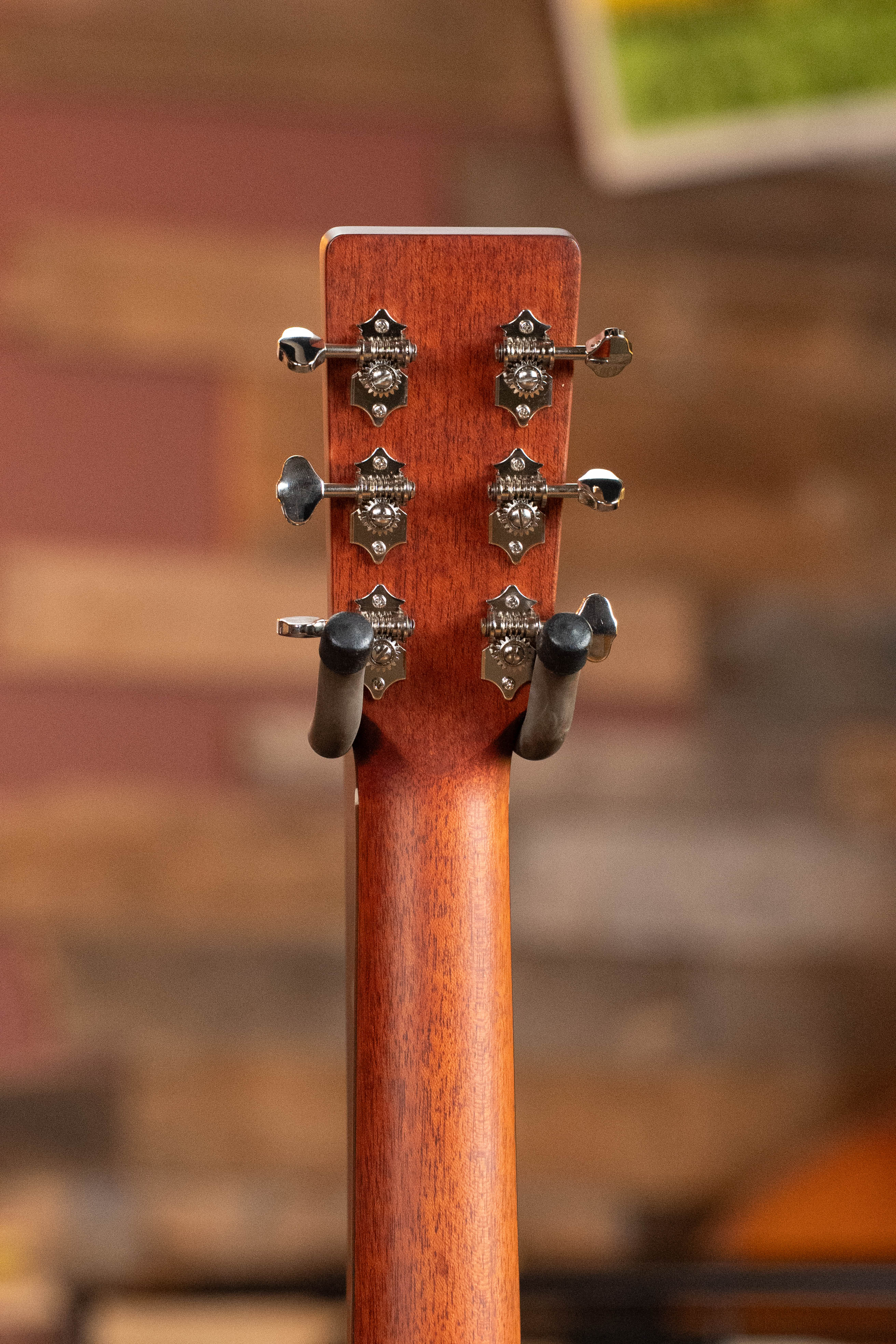 The Eastman Guitars E1D-DLX Sitka/Sapele Dreadnought Guitar #7721 features six metal tuning pegs on the headstock, is shown on a stand with a wood and red background, and includes a Fishman pickup for versatile amplification.