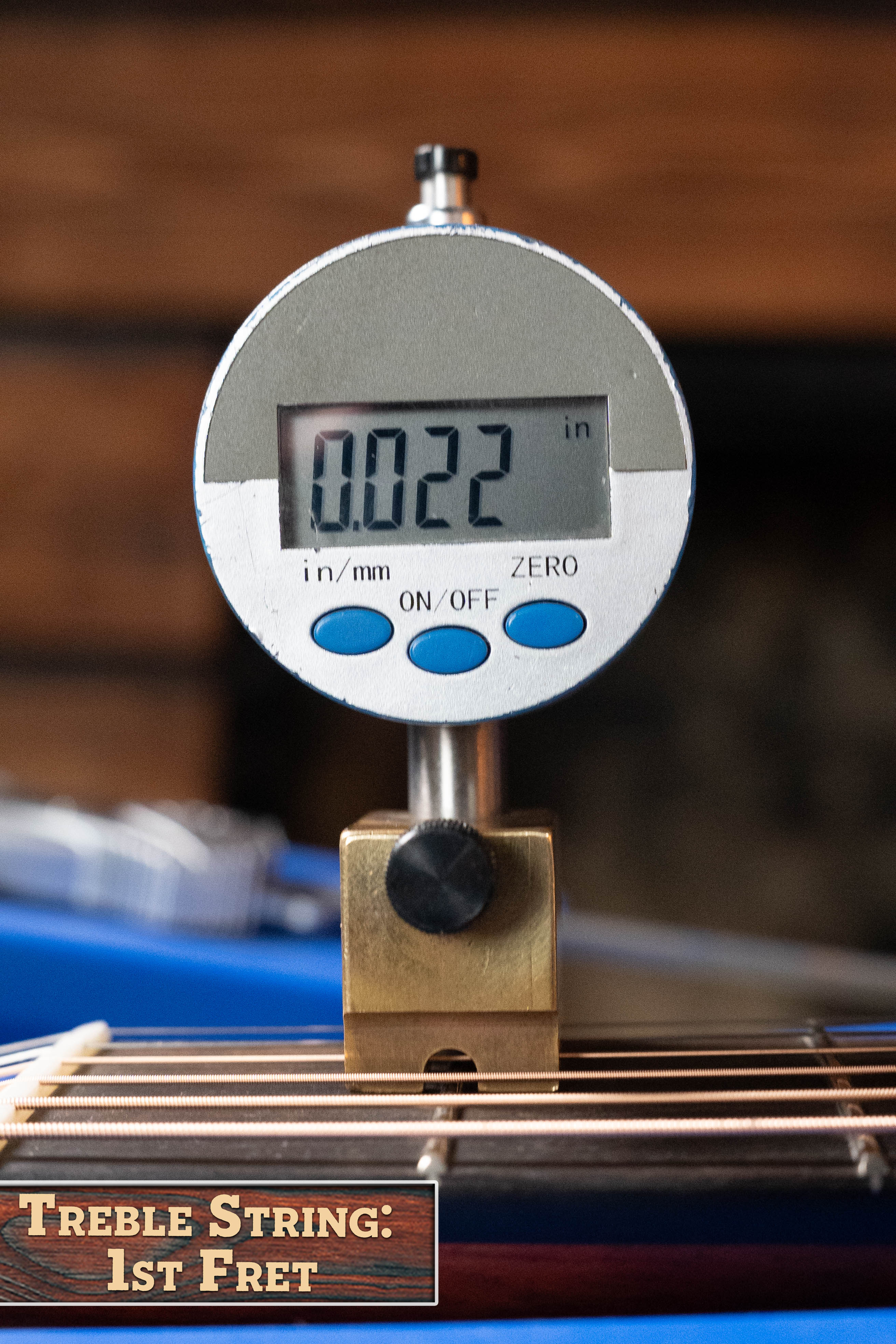 A digital gauge shows 0.022 in while measuring the treble string height above the 1st fret on an Eastman Guitars E1D-DLX Sitka/Sapele Dreadnought w/Fishman Pickup #7721. A sign reads: Treble String: 1st Fret.