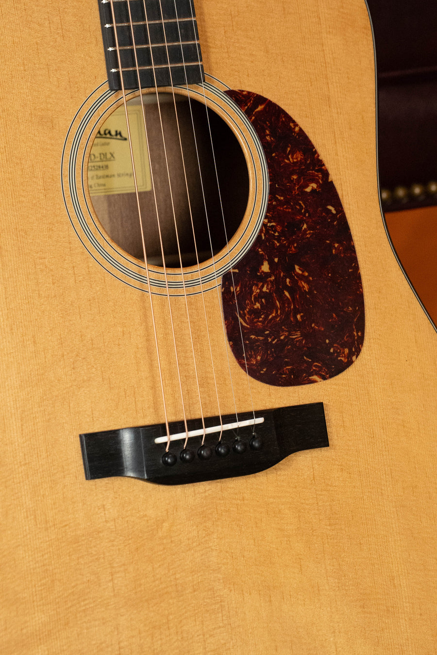 Close-up of the Eastman Guitars E1D-DLX Sitka/Sapele Dreadnought Guitar w/Fishman Pickup #8436, showing the body, sound hole with visible label, pickguard, bridge, six strings, wood grain, and Fishman pickup.