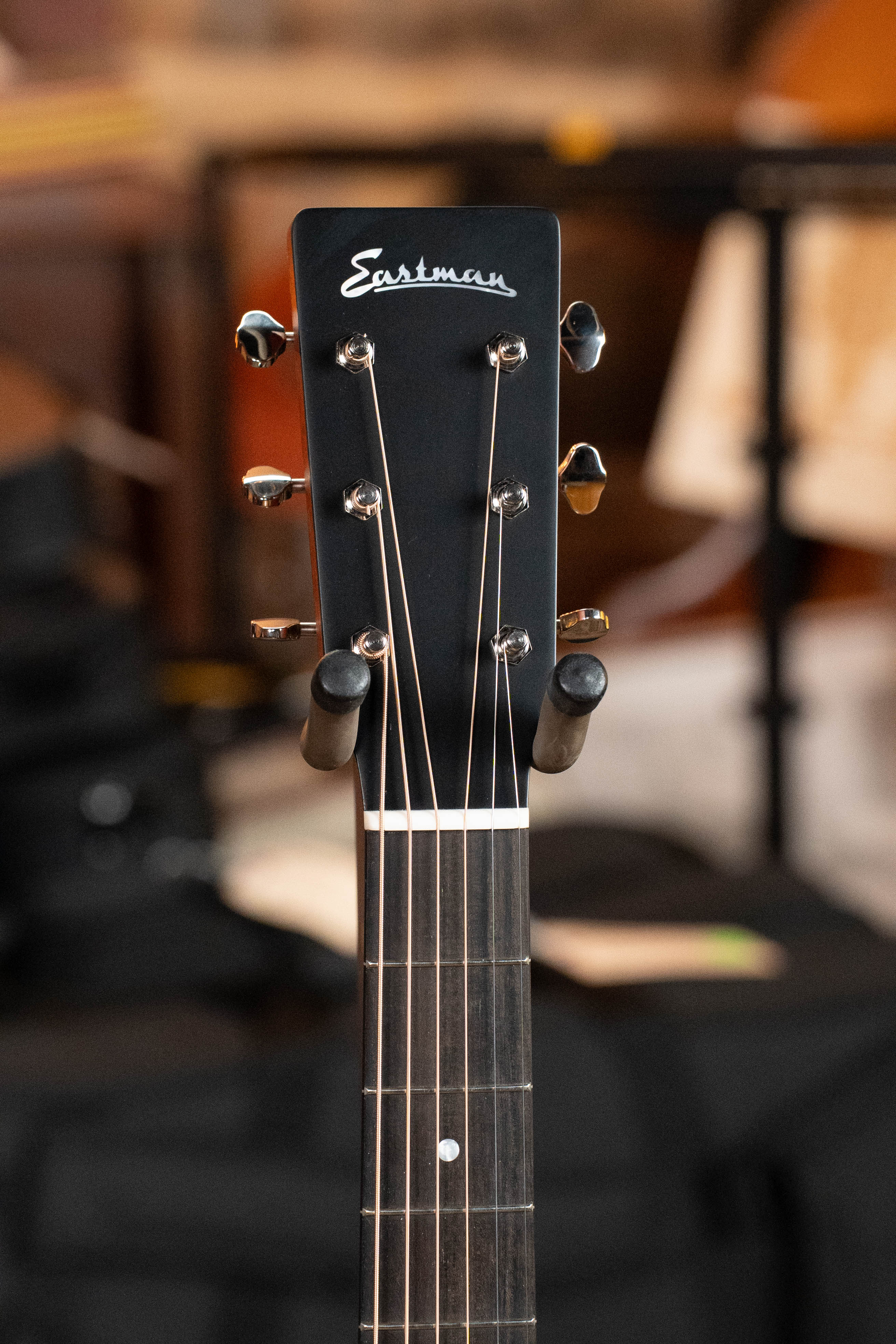 Close-up of the Eastman Guitars E1D Sitka/Sapele Dreadnought Acoustic Guitar #6855 headstock, showing its white script logo, six tuning pegs, and part of the fretboard; solid Sitka spruce top not shown in this detail shot.