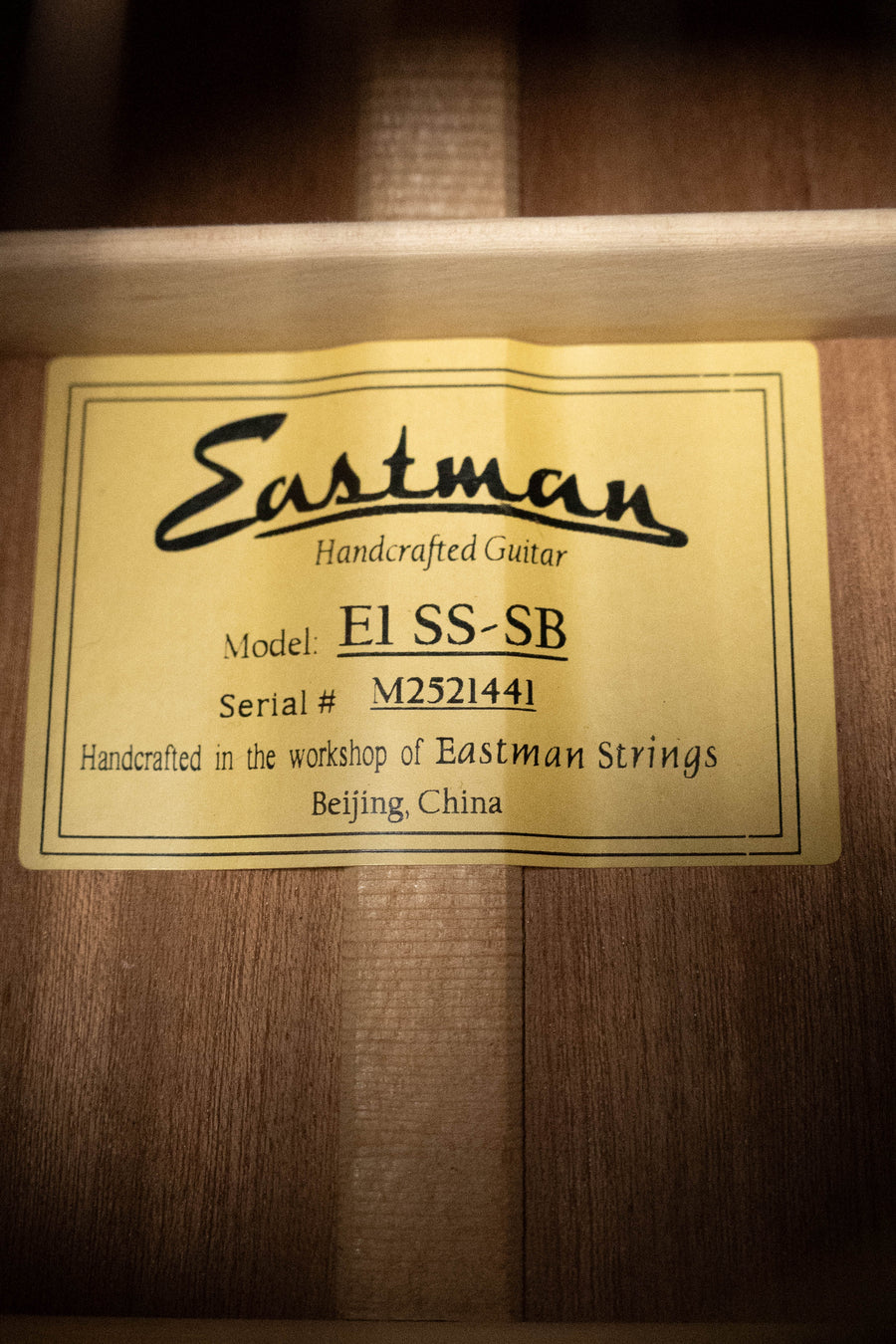 A yellow label inside this Eastman E1SS-SB Sitka/Sapele Sunburst Slope Shoulder Dreadnought (#1441) reads: Eastman Guitars, Model: E1SS-SB, Serial #: M2521441, Handcrafted in Beijing, China.