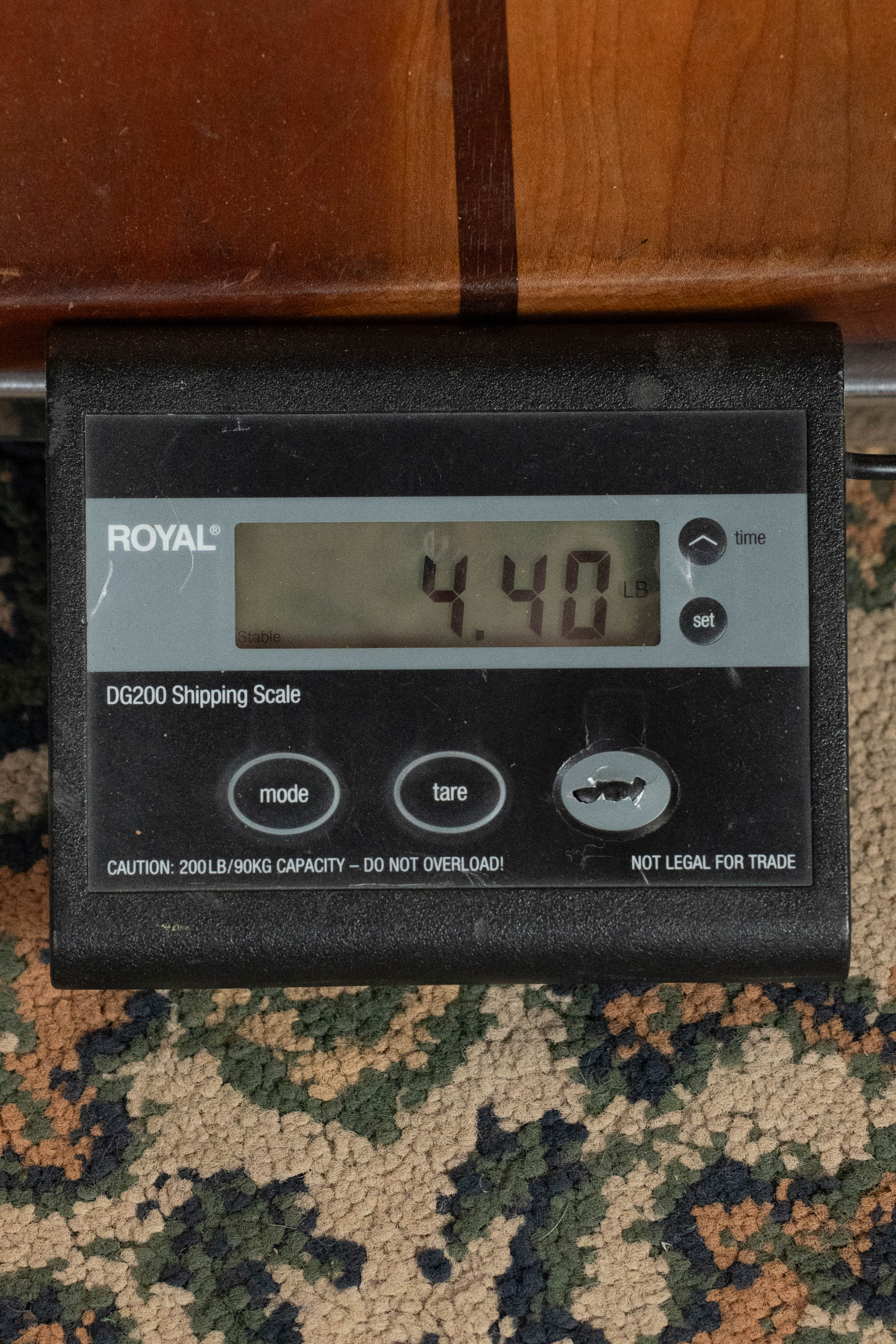 A digital shipping scale on a patterned carpet shows 4.40 pounds—ideal for weighing items like the Eastman Guitars E20D-LSH-TC Thermo-Cured Adirondack/Rosewood Large Soundhole Dreadnought Acoustic Guitar #8072.