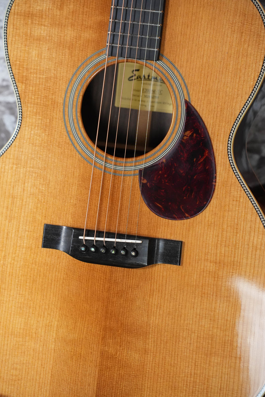 Close-up of the Eastman Guitars E20OM-TC Thermo-Cured Adirondack/Rosewood Orchestra Model Acoustic Guitar #2768, featuring six steel strings, soundhole with label, dark tortoiseshell pickguard, and glossy Adirondack spruce finish.
