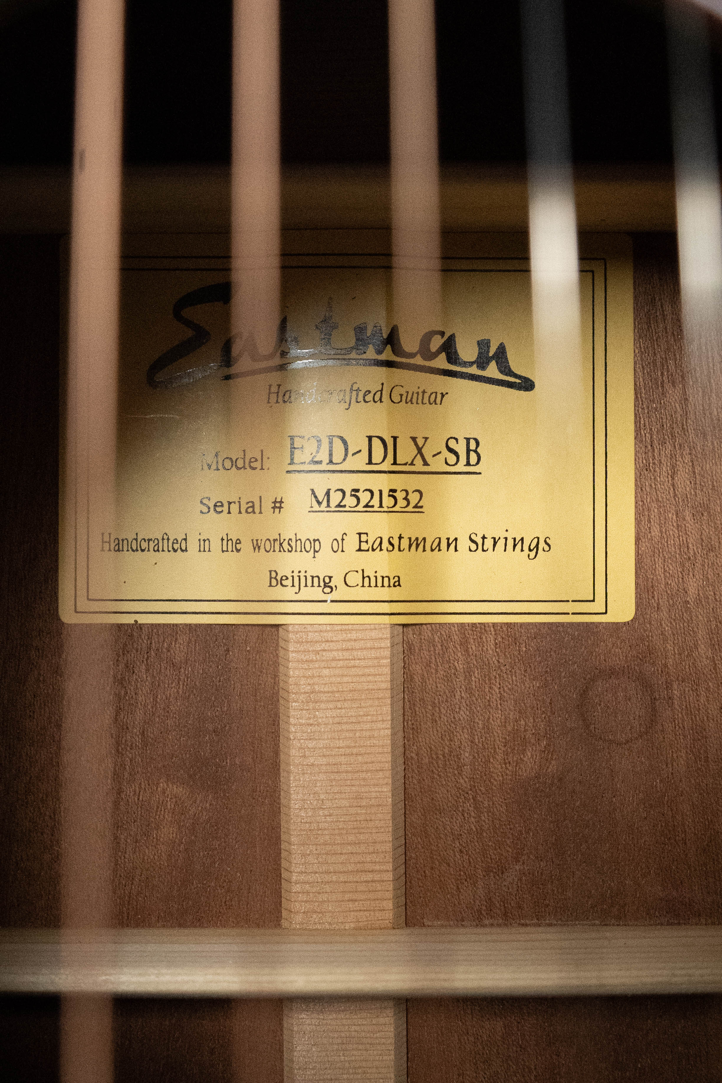 Close-up of an Eastman Guitars E2D-DLX-SB Cedar/Sapele Sunburst Dreadnought Guitar w/Fishman Pickup (#1532) label, showing it's handcrafted in the Eastman workshop, Beijing, China.
