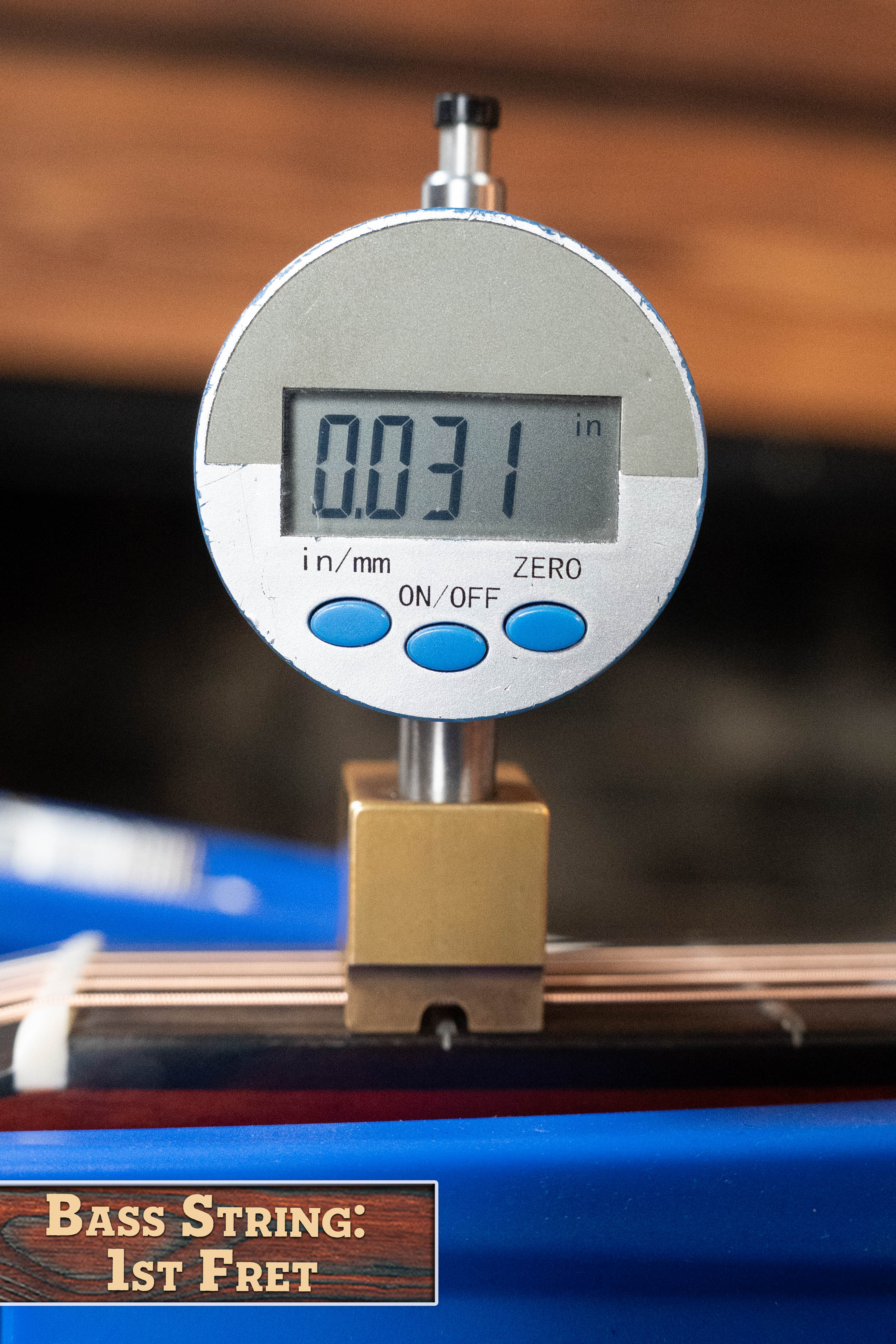 A digital gauge shows 0.031 inches for the bass string height at the 1st fret, beside a “Bass String: 1st Fret” label. Nearby, an Eastman Guitars E2D-DLX-SB Cedar/Sapele Sunburst Dreadnought w/Fishman Pickup #1532 gleams.