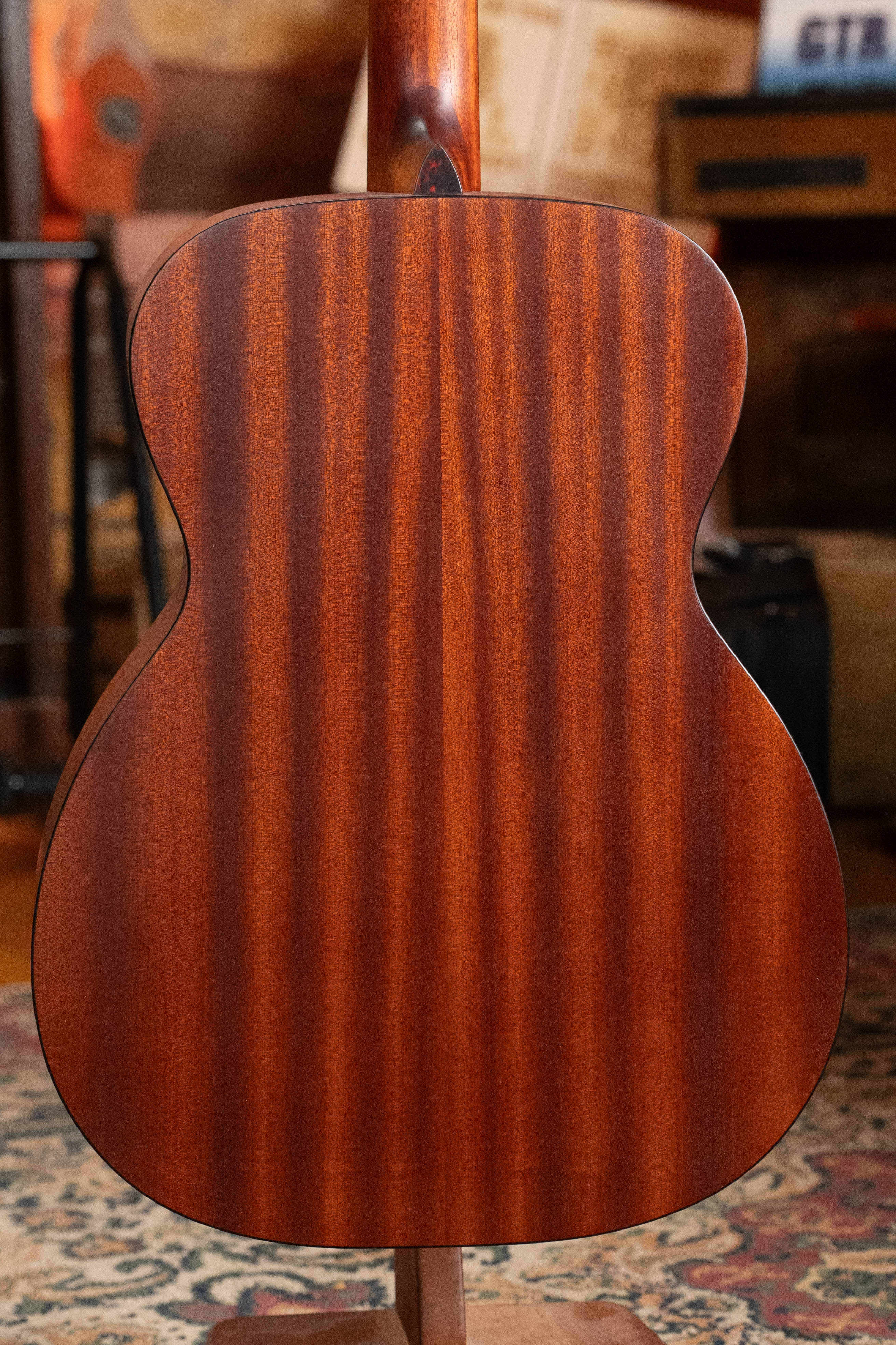A close-up of the back of the Eastman Guitars E2OM Cedar/Sapele Orchestra Model Acoustic Guitar #9002, showing its rich, reddish-brown wood and vertical grain—an ideal choice for fingerstyle players.