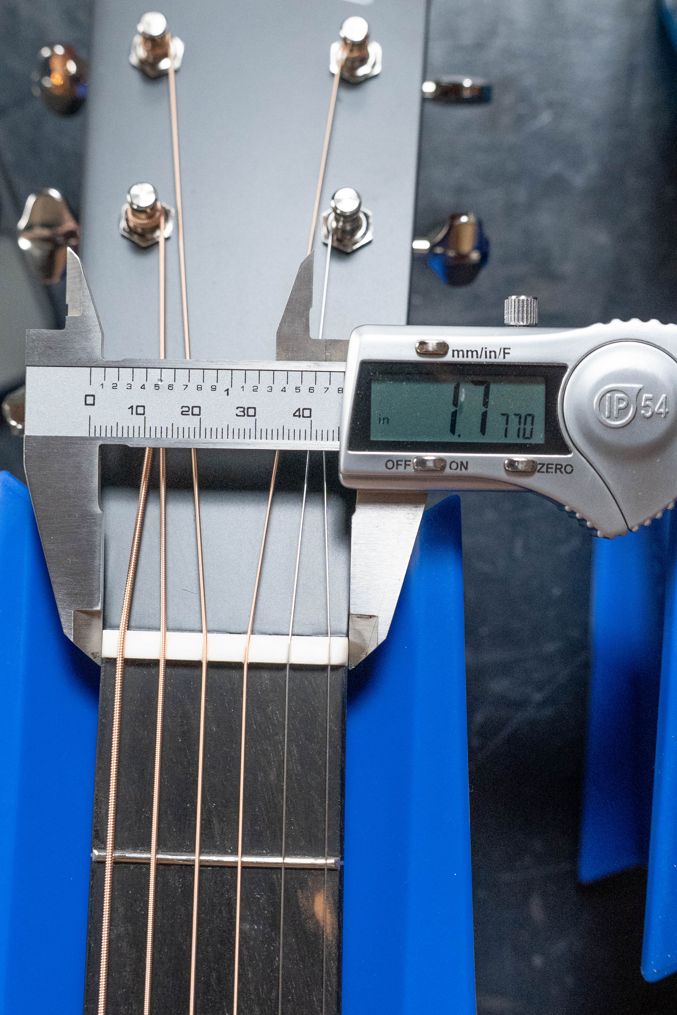 A digital caliper measures the Eastman Guitars E2OM Cedar/Sapele Orchestra Model (#9010) neck width at 1.770 inches, clamped across the six-string neck—ideal for fingerstyle players seeking precision.
