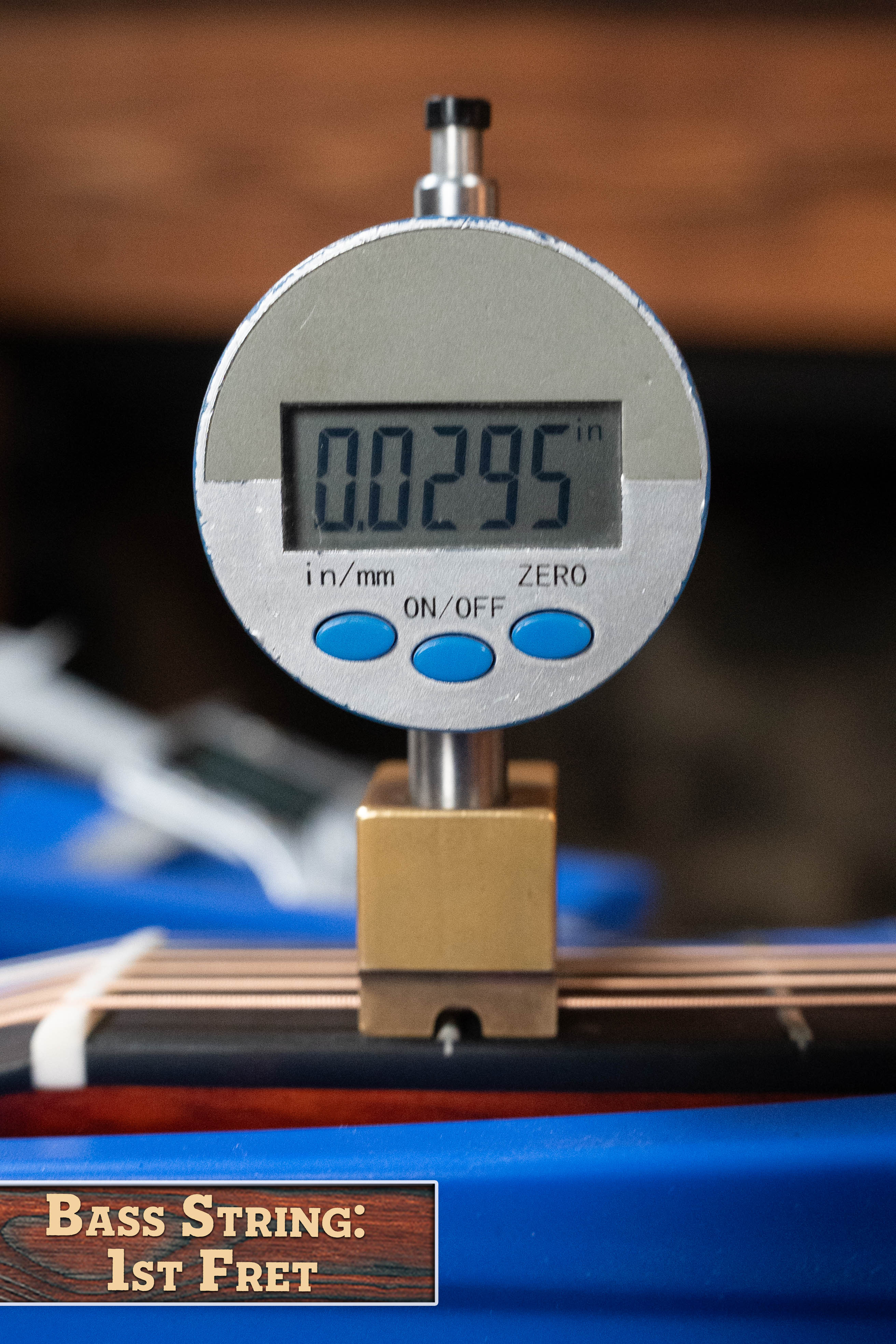 A digital caliper reads 0.0295" when measuring bass string height at the 1st fret of the Eastman Guitars E2OM Cedar/Sapele Orchestra Model Acoustic Guitar #9010, labeled: Bass String: 1st Fret.