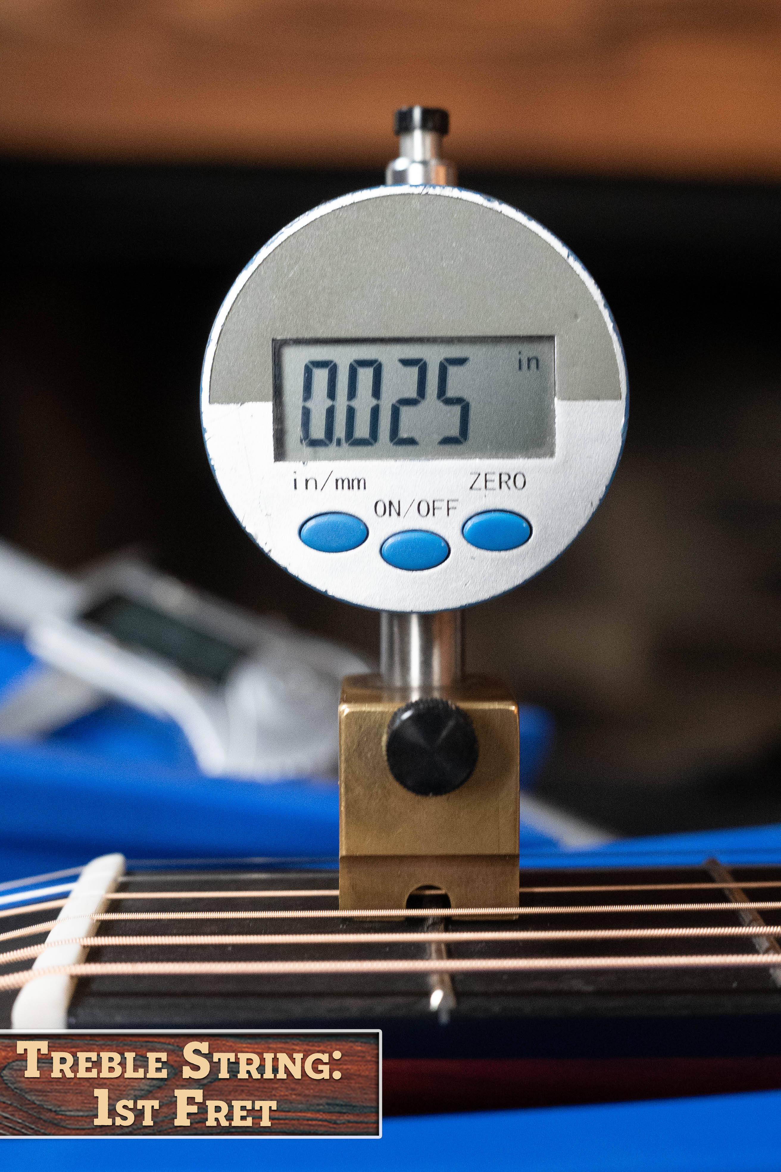 A digital gauge reads 0.025 inches when measuring the treble string height at the 1st fret on an Eastman Guitars E2OM Cedar/Sapele Orchestra Model Acoustic Guitar #9010. Label: Treble String: 1st Fret.