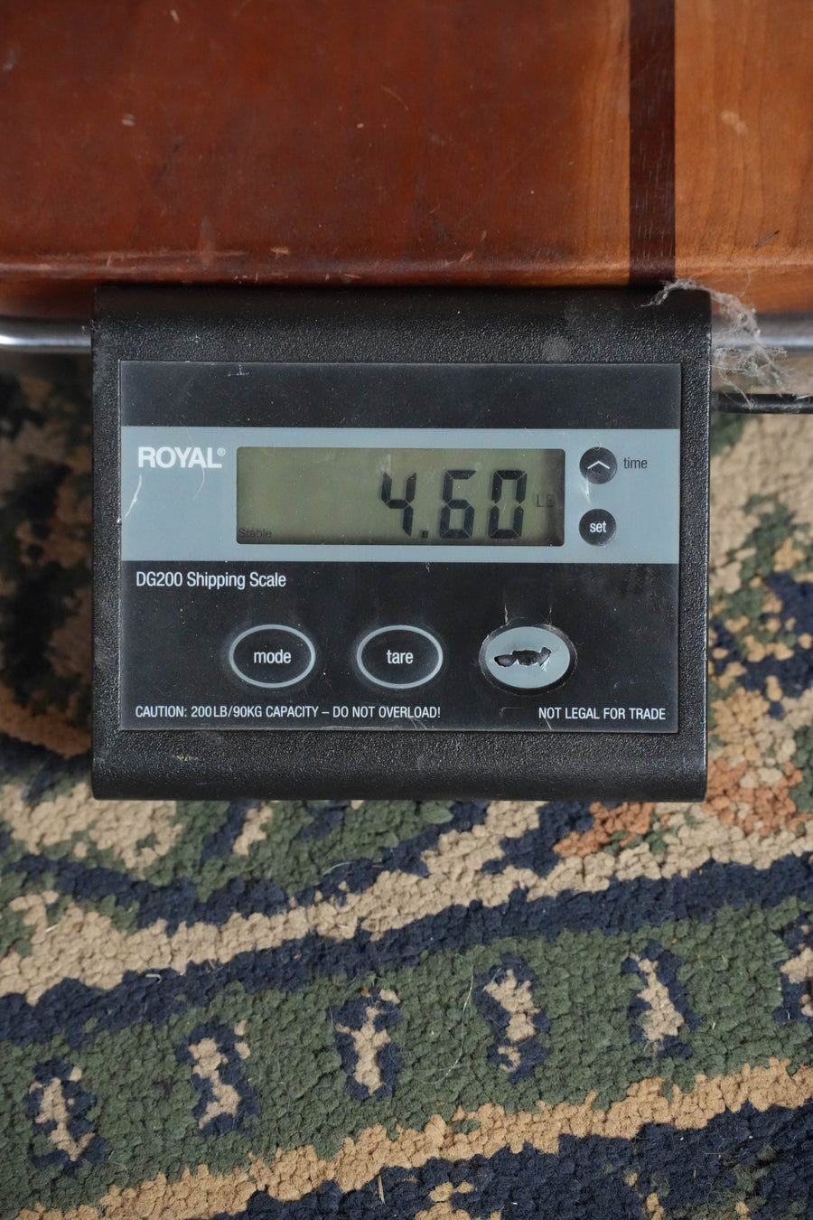 A digital shipping scale reads 4.60 pounds on a multicolored rug, with part of an Eastman Guitars E40D-TC-SB Thermo-cured AAA Grade Adirondack/Rosewood Sunburst Dreadnought Acoustic Guitar #5274 resting on it.