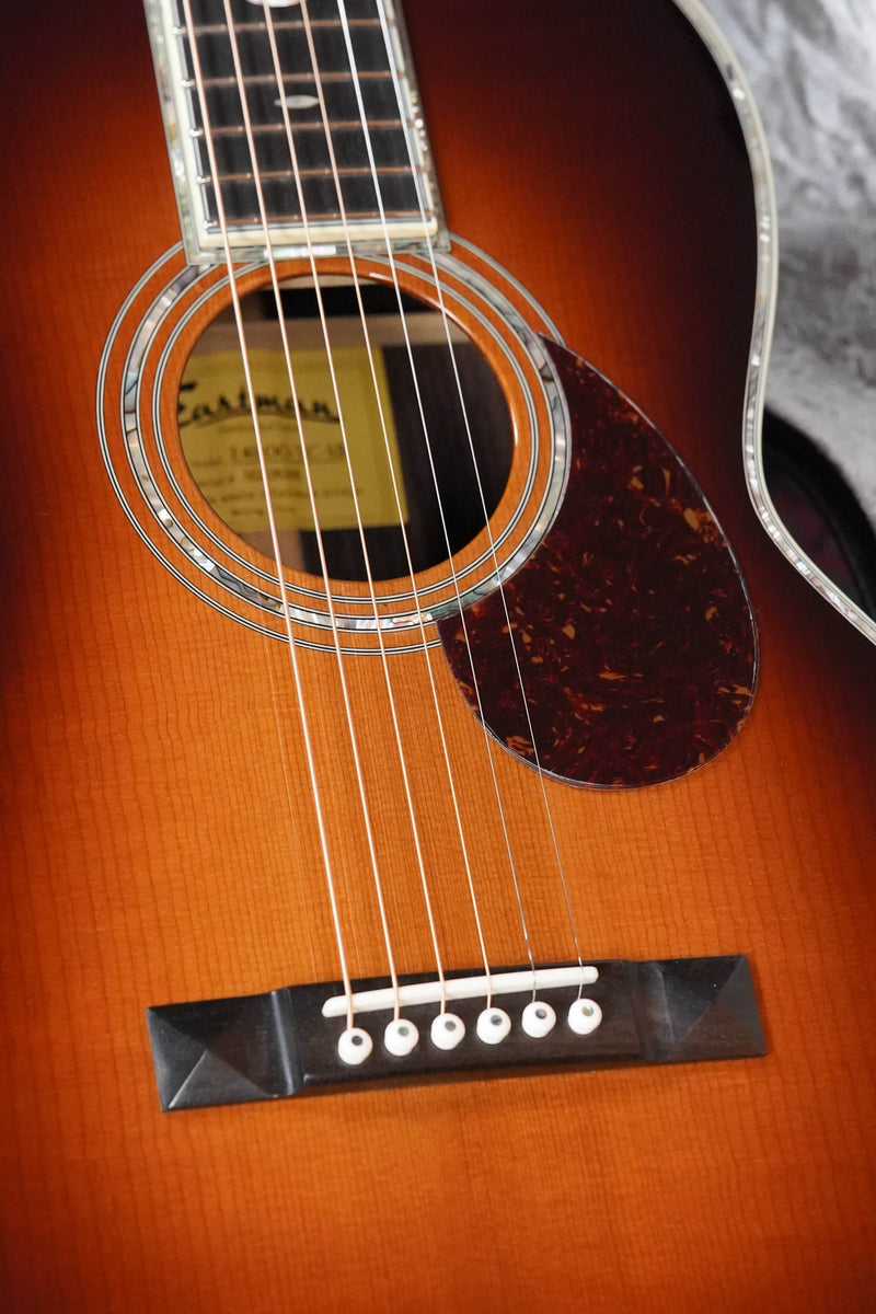 Close-up of the Eastman Guitars E40OO-TC-SB #8266 OO acoustic, showcasing an AAA grade thermo-cured Adirondack spruce top, rosewood back and sides, six strings, wood bridge with white pins, tortoiseshell pickguard, and ornate rosette on a sunburst finish.