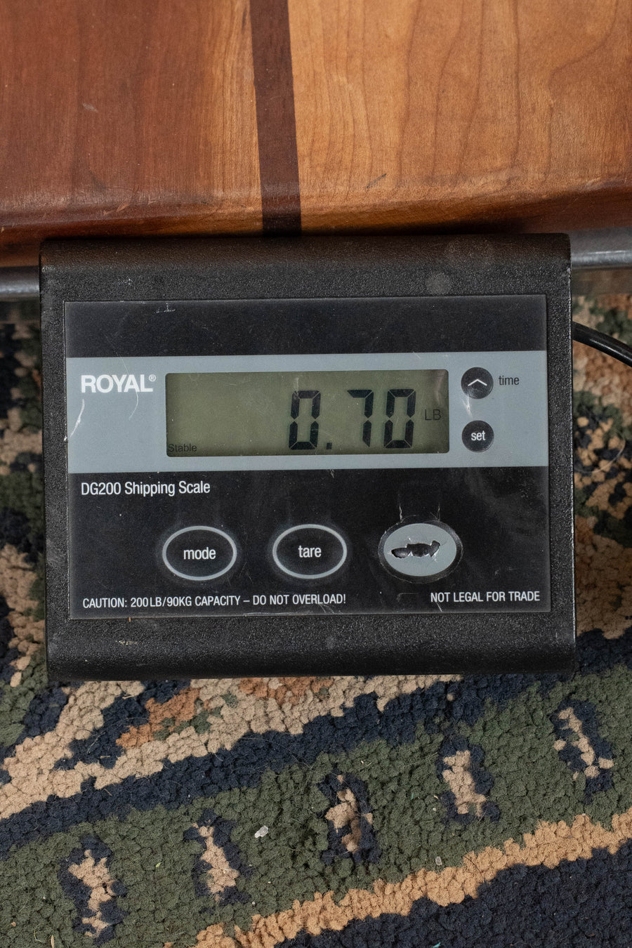 A digital shipping scale reads 0.70 pounds, ideal for tracking your Eastman EU2-s Sitka/Rosewood Soprano Ukulele #2071 by Eastman Guitars. The ROYAL DG200 rests on patterned carpet next to a wooden surface.