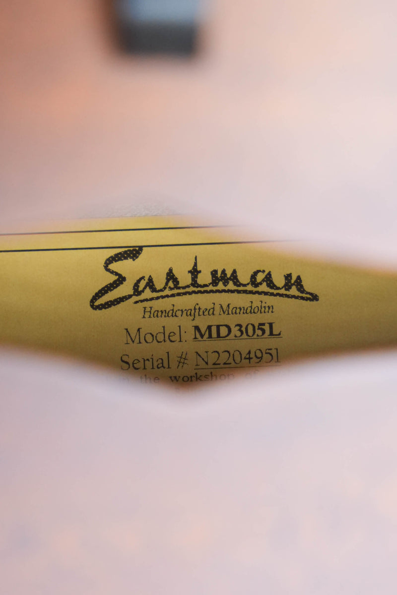 Close-up view through the f-hole of an Eastman Guitars MD305L Left-Handed Spruce/Maple A-Style Hand-Carved Mandolin (#4951), showing a yellow label inside with the product details.