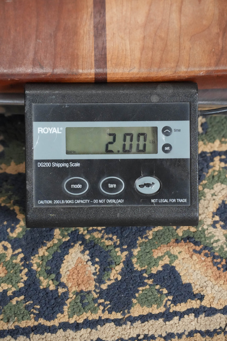 A Royal DG200 digital shipping scale shows 2.00 lbs while on a rug under wood—ideal for weighing instruments like the Eastman Guitars MD315 F-Style Hand-Carved Mandolin #0107, known for its professional-level tone.