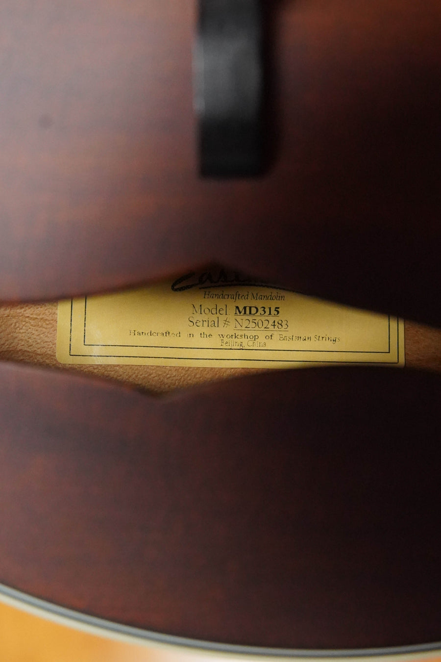 Close-up of a label inside the Eastman Guitars MD315 F-Style Hand-Carved Mandolin #2483, highlighting its model number and craftsmanship—a mark of professional quality.