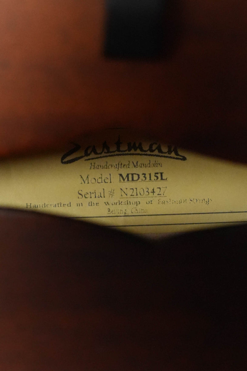 A close-up of the label inside an Eastman Guitars MD315L Left-Handed F-Style Hand-Carved Mandolin #3427, indicating it was crafted from spruce and maple for professional tone in Beijing, China.