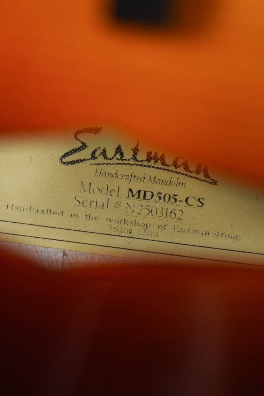 Close-up of a label inside an Eastman Guitars MD505-CS Spruce/Maple Classic Sunburst A-Style Mandolin #3162, handcrafted in Beijing, China.