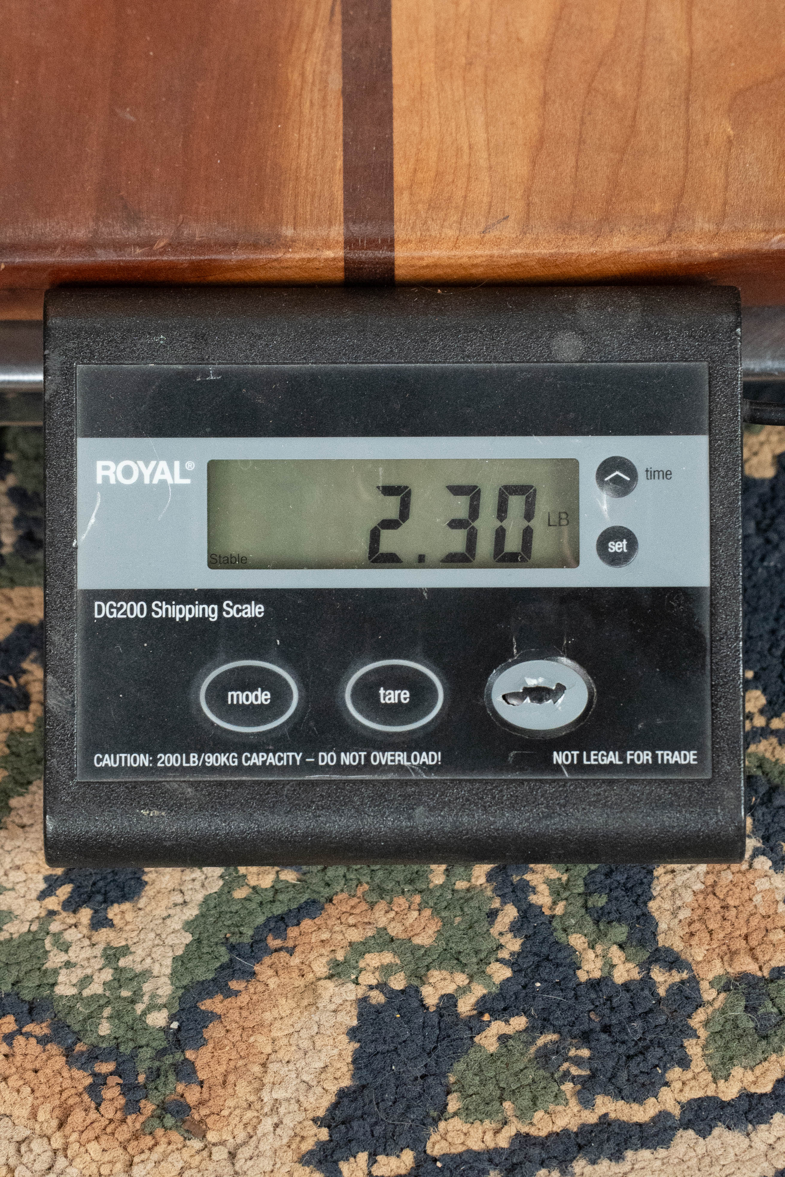 A digital shipping scale reads 2.30 pounds while resting on carpet next to an Eastman Guitars MD615 Spruce/Maple F-Style Mandolin w/K&K Pickup #3918; the scale features mode, tare, and set buttons.