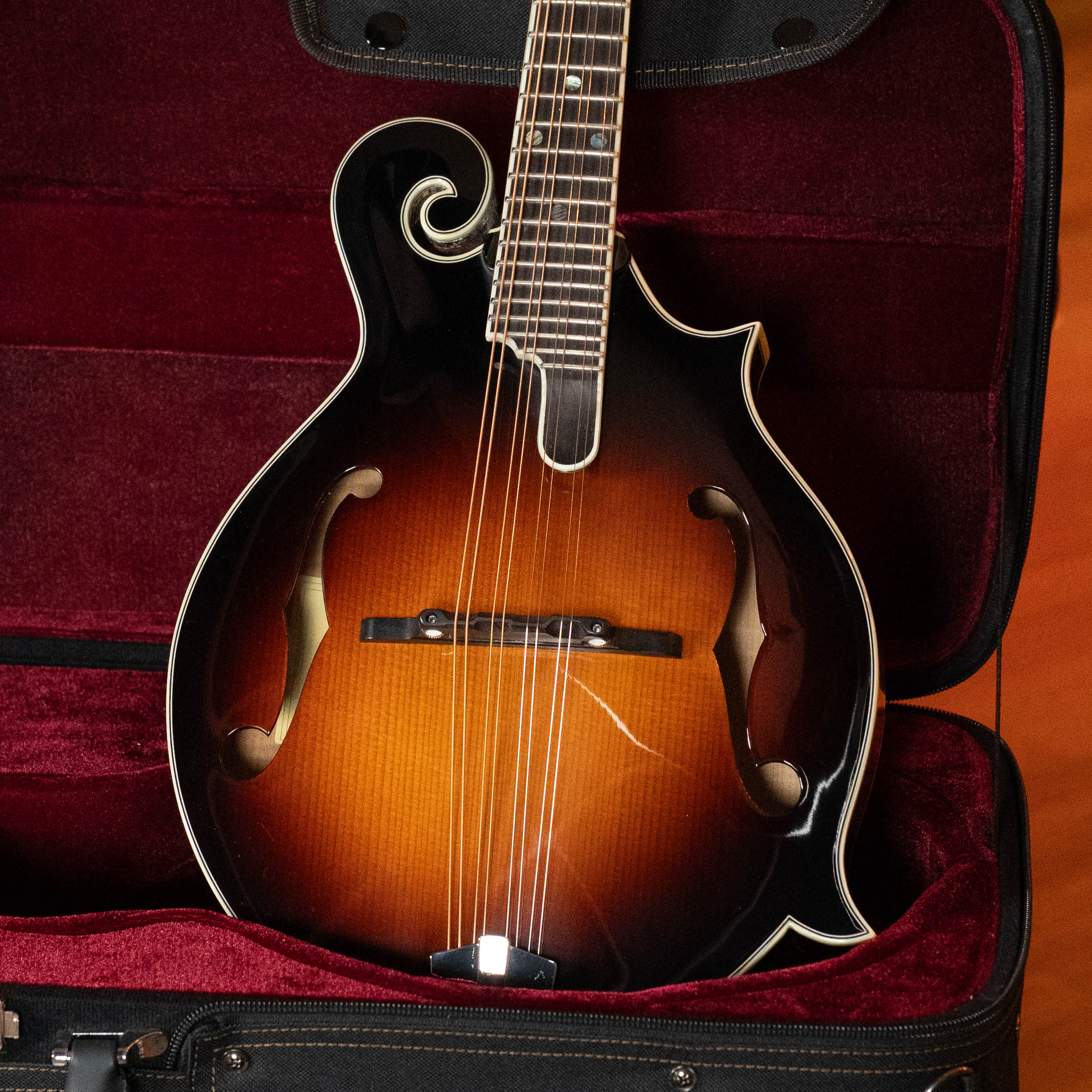 An Eastman Guitars MD815-SB Adirondack/Flamed Maple Sunburst F-Style Mandolin #3355 with a glossy finish rests in an open, red velvet-lined hard case.