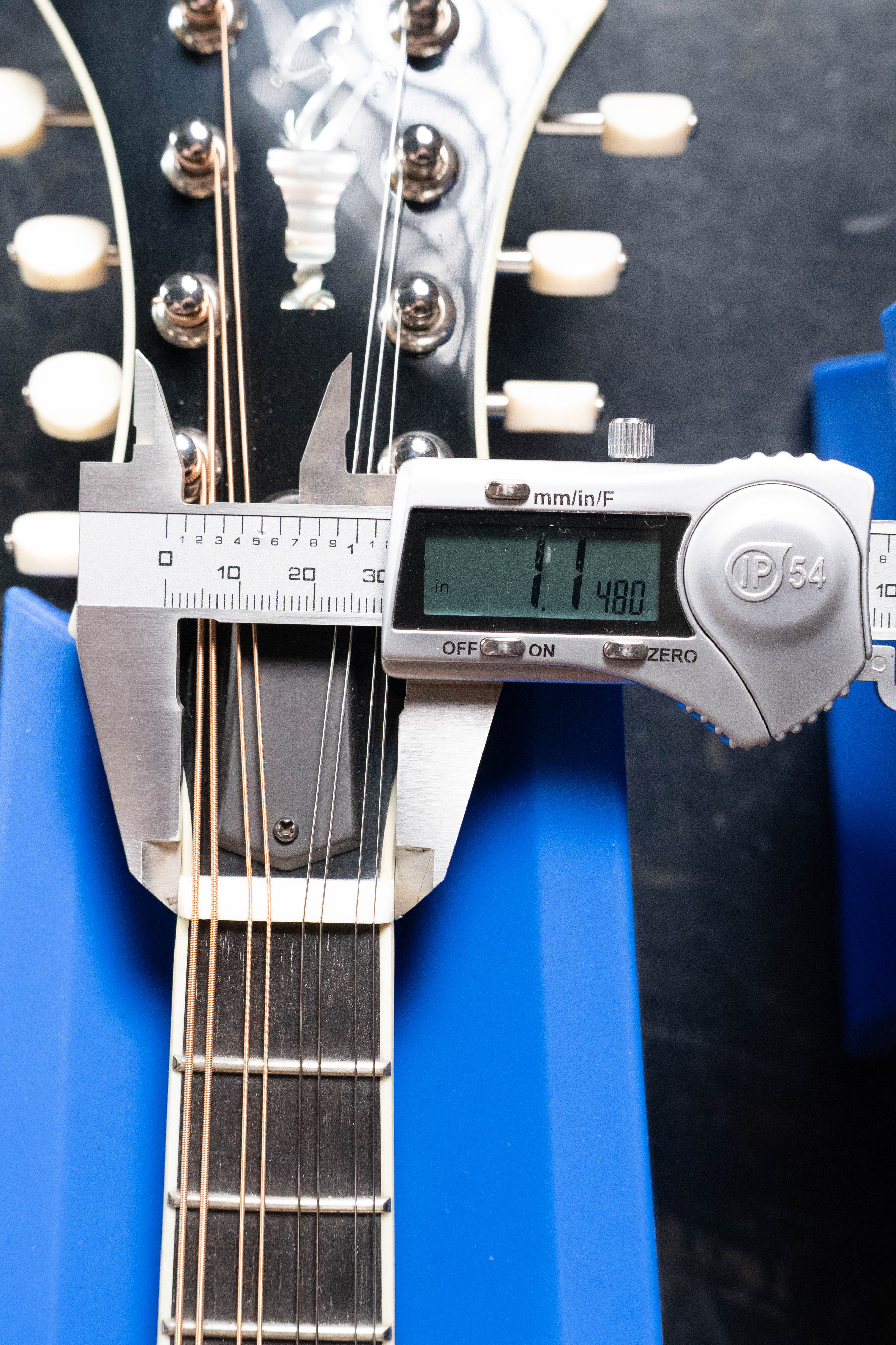 A digital caliper shows the Eastman Guitars MD815-SB Adirondack/Flamed Maple Sunburst F-Style Mandolin #3355 neck width at the nut as 1.480 inches, with its headstock and tuners visible while resting on blue supports.