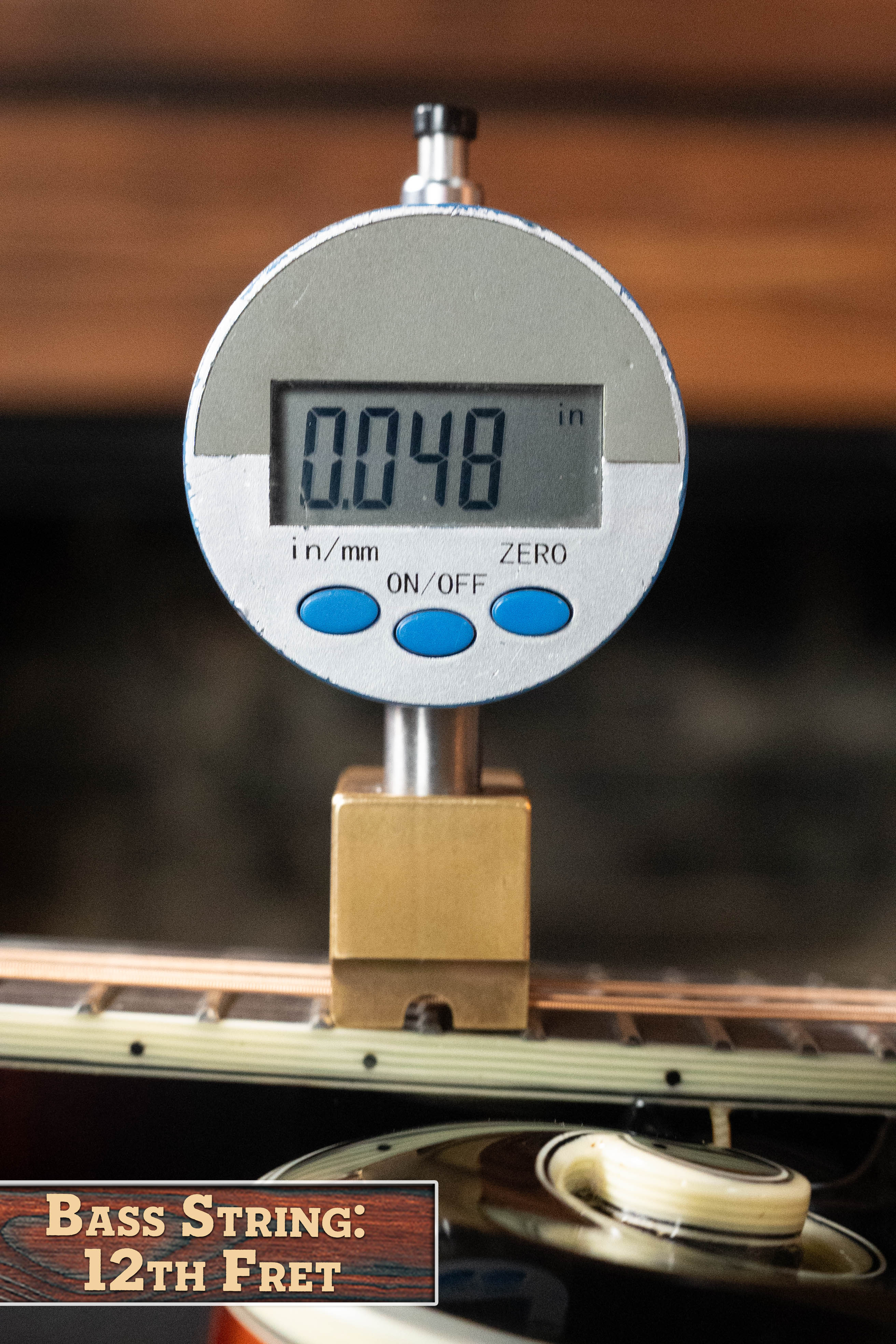 A digital gauge reads 0.048 inches for a bass string at the 12th fret—ideal for setups with the Eastman Guitars MD815-SB Adirondack/Flamed Maple Sunburst F-Style Mandolin #3355.