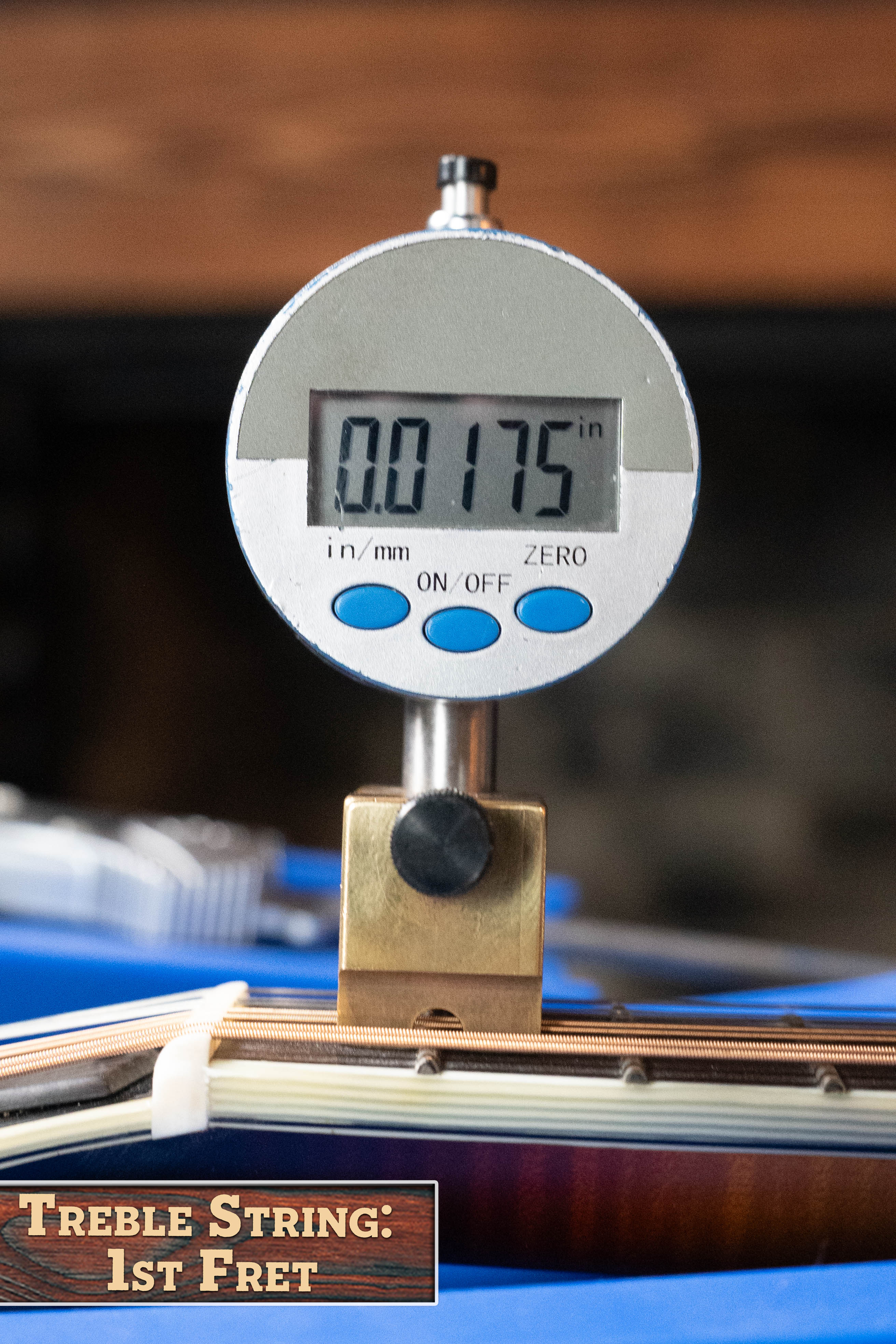 A digital gauge shows 0.0175 in while measuring string height at the 1st fret of an Eastman MD815-SB Adirondack/Flamed Maple Sunburst F-Style Mandolin (#3355) by Eastman Guitars. A sign reads Treble String: 1st Fret.
