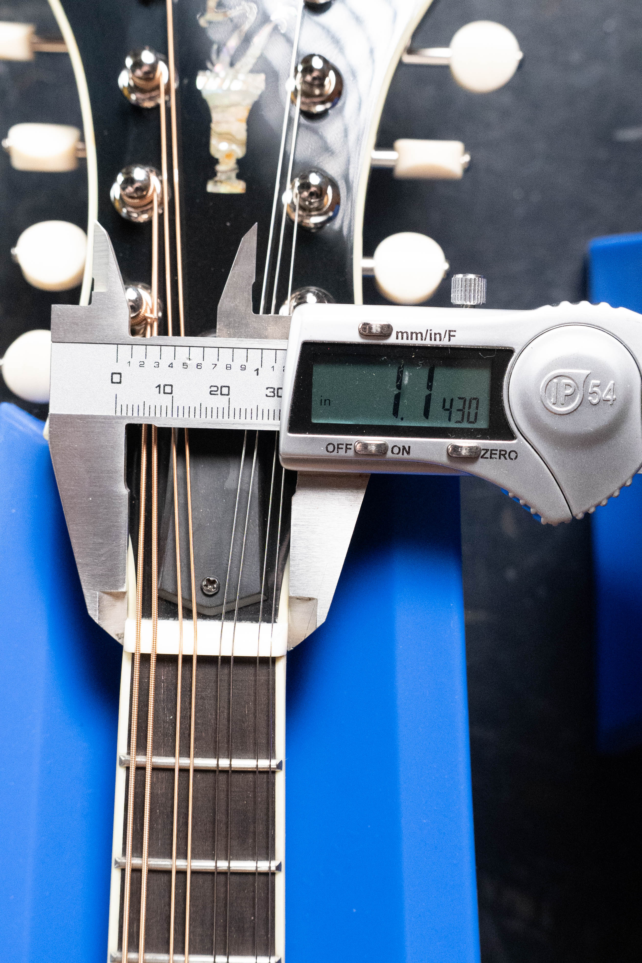A digital caliper measures the neck width near the nut of an Eastman MD815-SB Adirondack/Flamed Maple Sunburst F-Style Mandolin #3356 by Eastman Guitars, displaying 1.430 inches; its distinctive headstock and tuning pegs appear in the background.