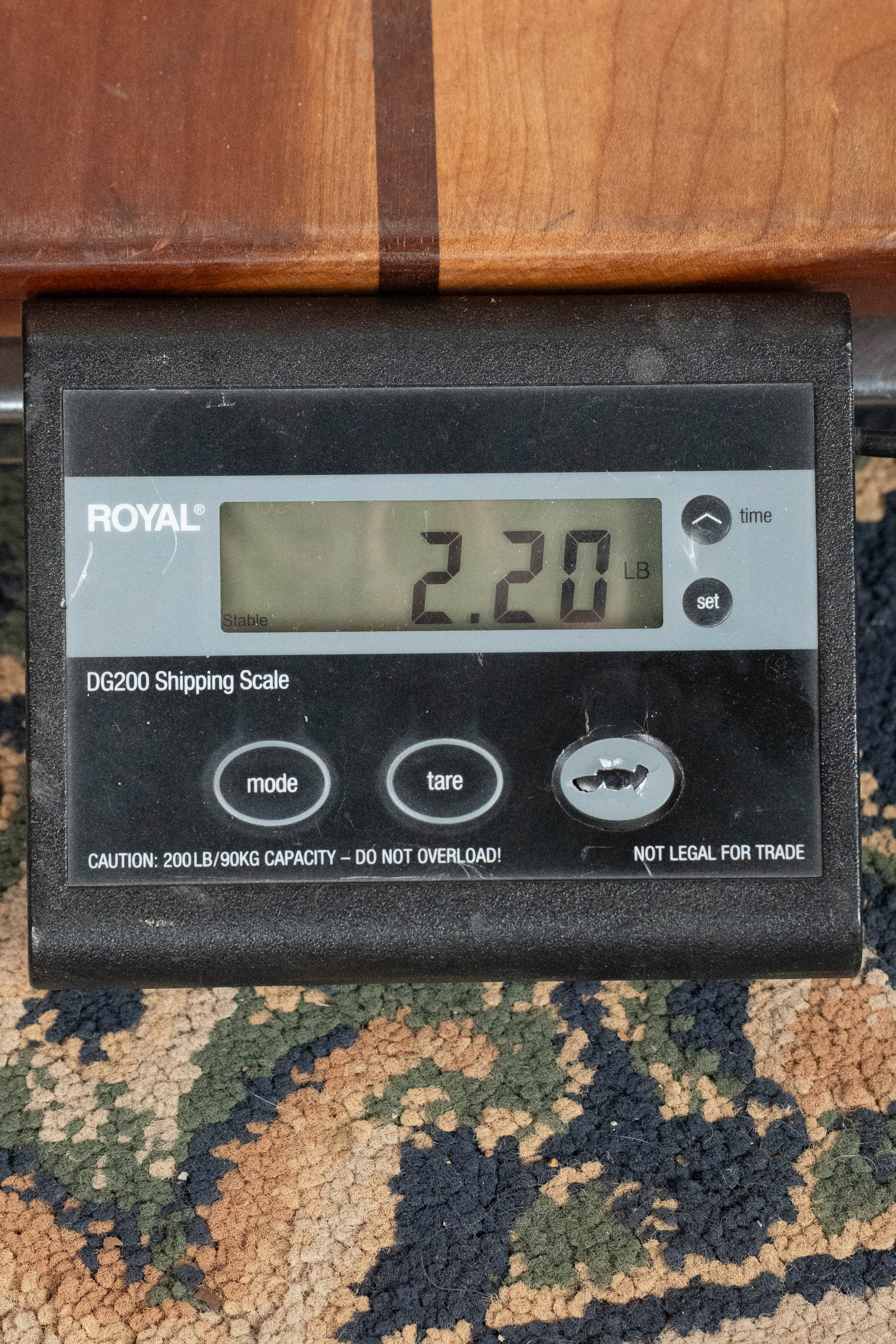 A digital shipping scale shows 2.20 pounds as part of an Eastman Guitars MD815-SB Adirondack/Flamed Maple Sunburst F-Style Mandolin (#3356) rests on it. The black scale with buttons sits on a patterned carpet.